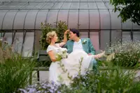 Hochzeitsfotograf im Botanischen Garten Karlsruhe: Brautpaar entspannt auf einer Bank zwischen Blumen nach der Trauung.