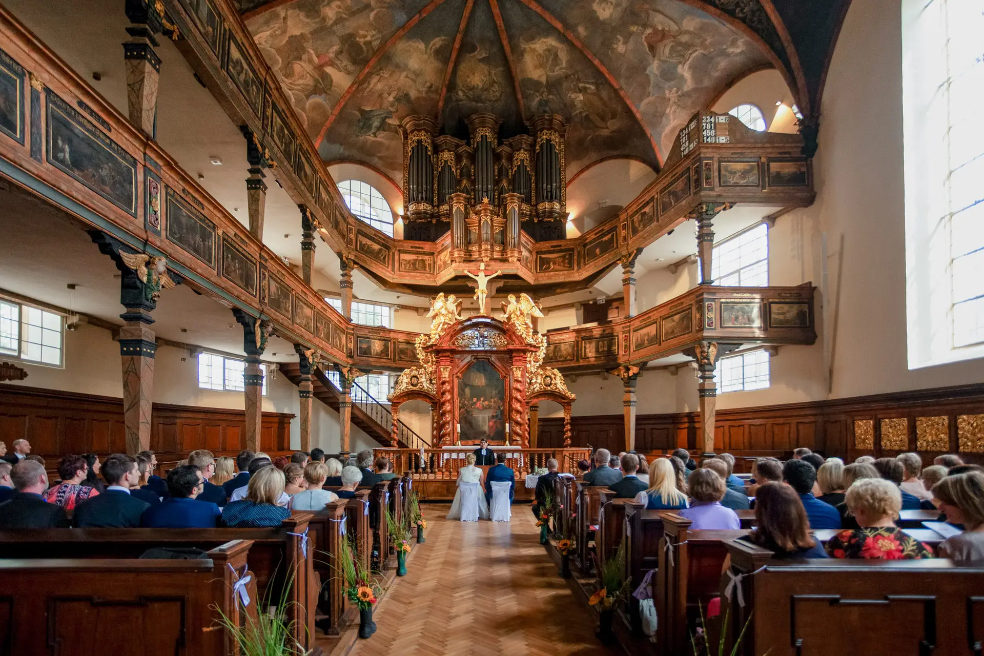 Brautpaar vor Altar in prachtvoller historischer Kirche mit Stuckdecken