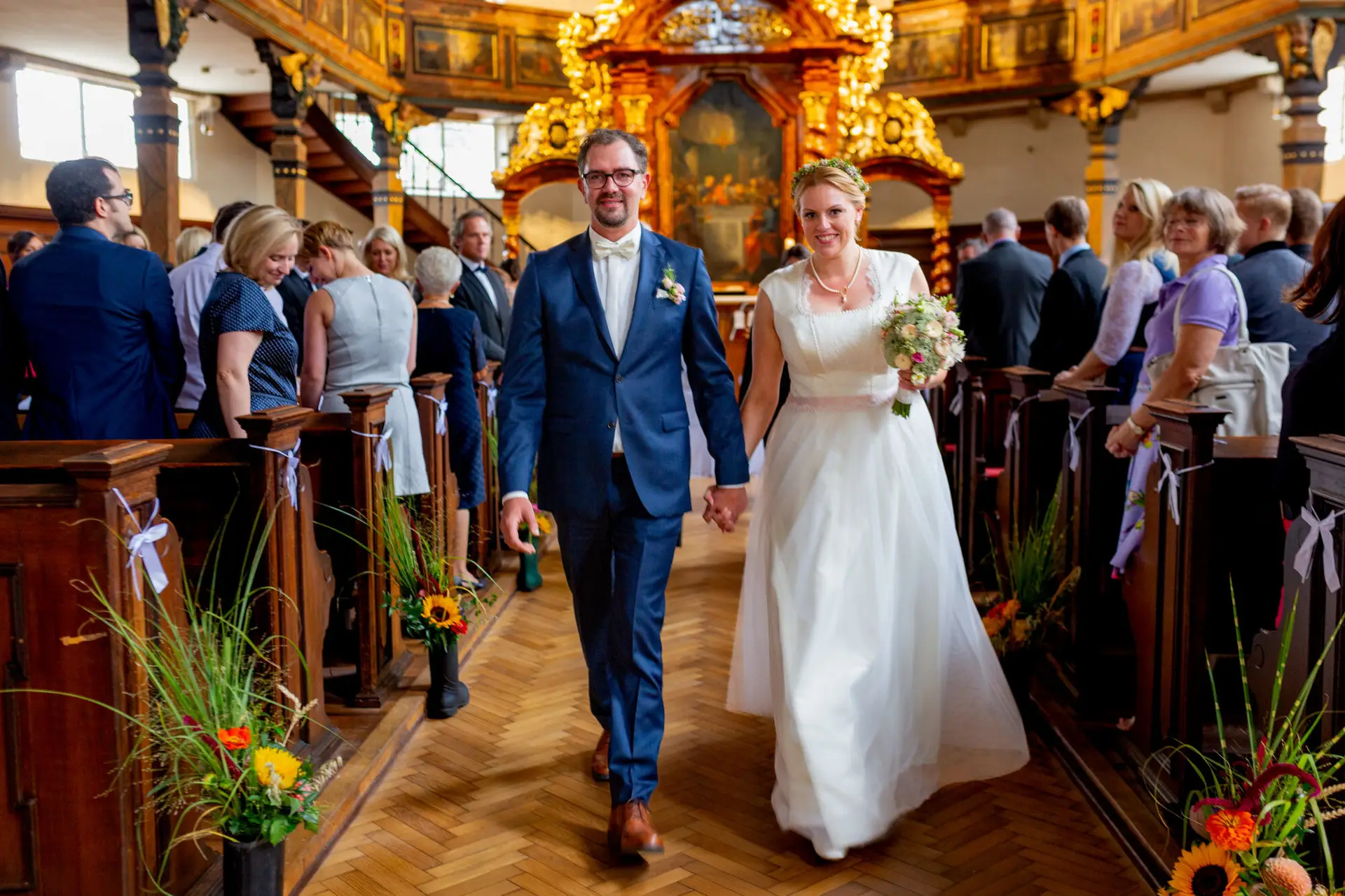 Brautpaar geht Hand in Hand durch das Kirchenschiff nach der Trauung