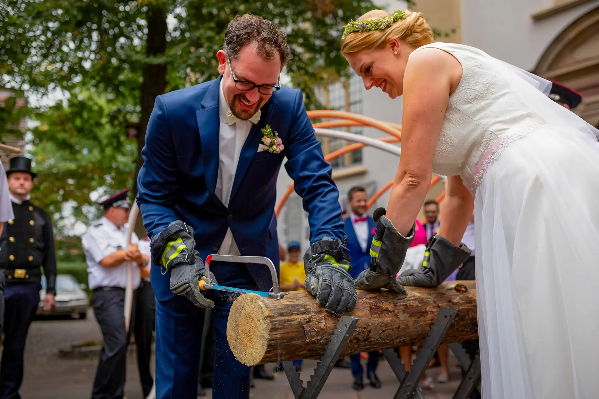 Brautpaar sägt gemeinsam einen Holzstamm beim traditionellen Baumstammsägen