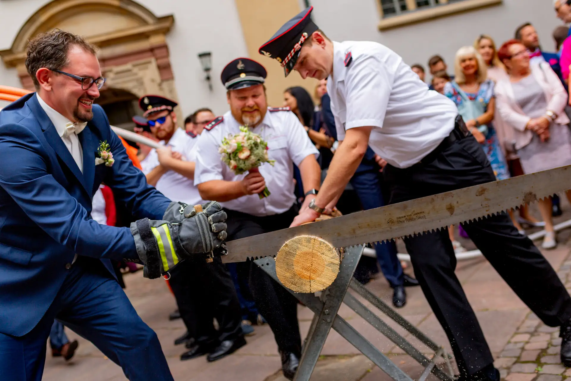 Brautpaar schafft gemeinsam den Holzstamm beim Baumstammsägen vor der Kirche