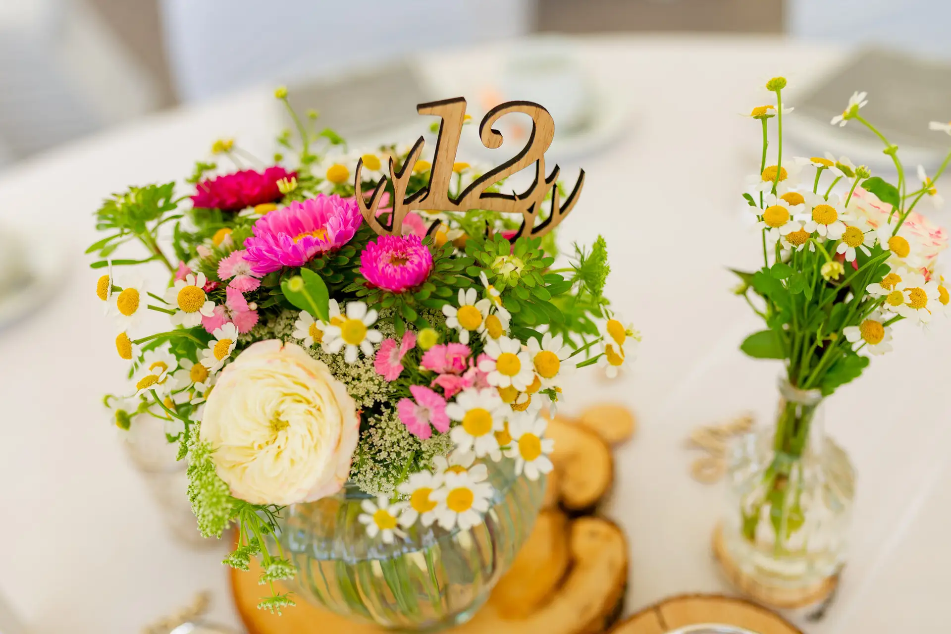 Fröhliche Blumenarrangements in kleinen Glasvasen am Hochzeitstisch