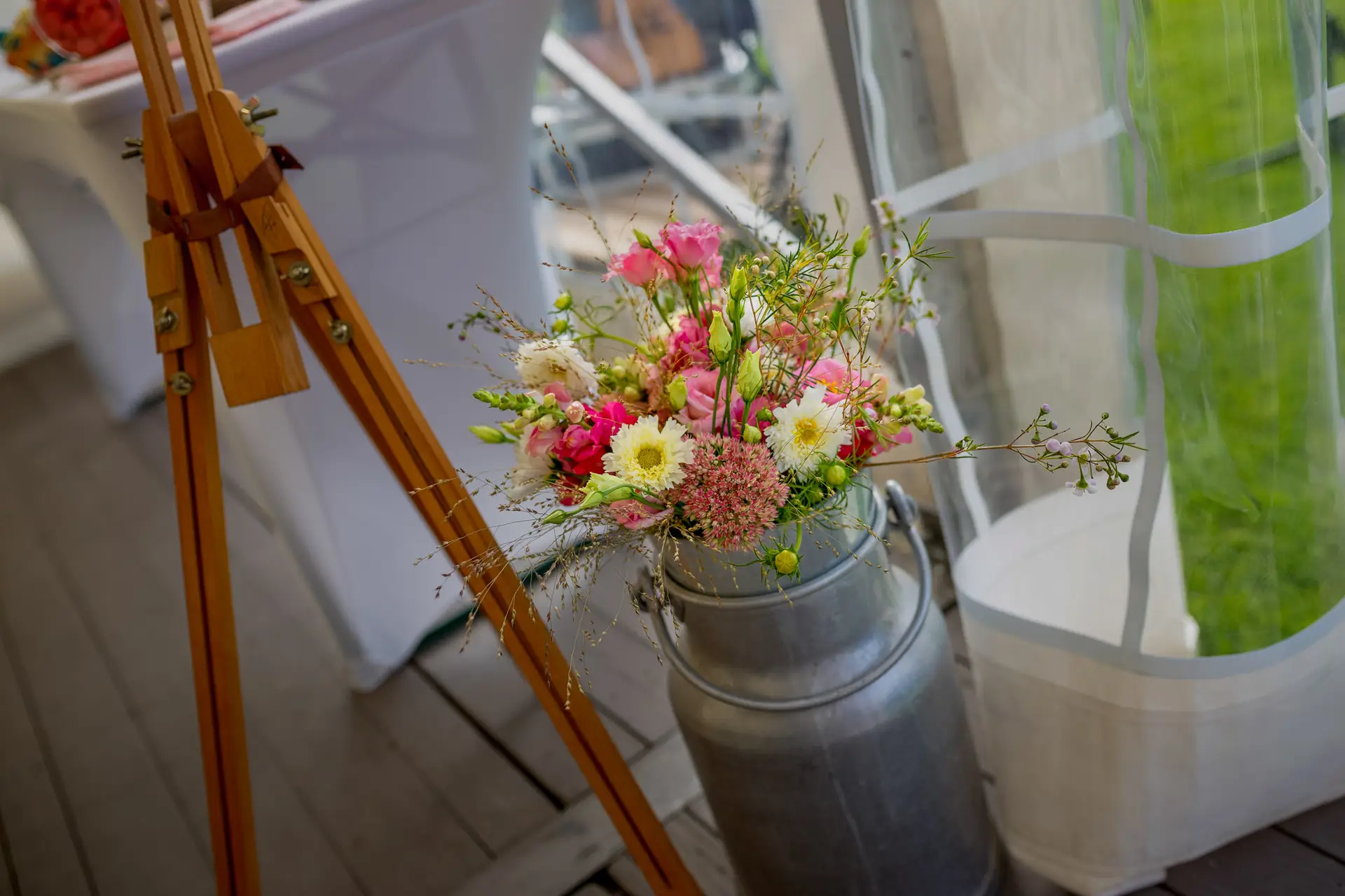 Blumenstrauß, Holzgestell und alte Metallkanne als Deko im Festzelt