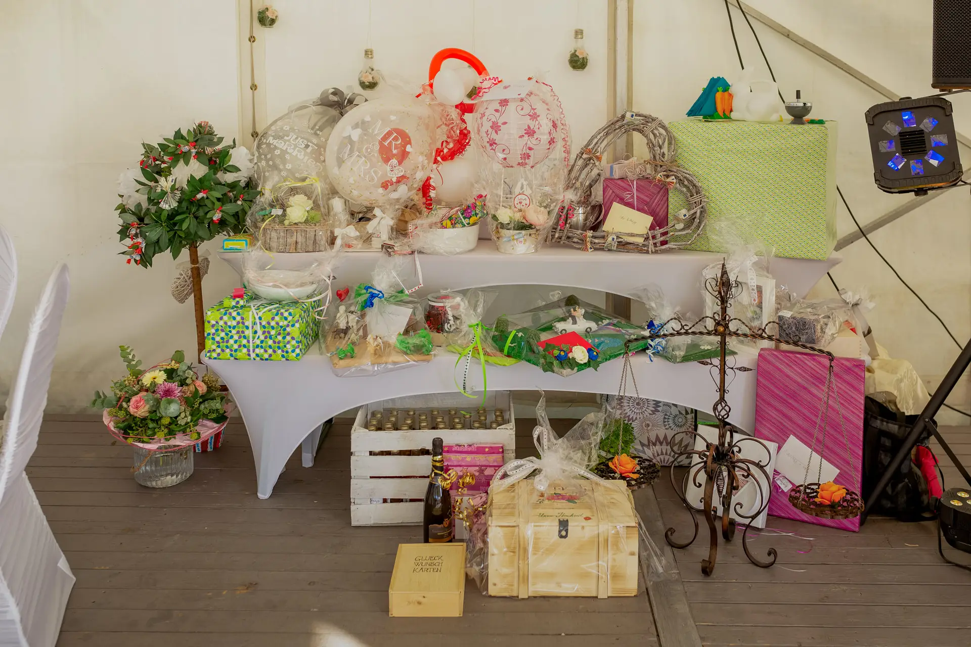 Hochzeitsszene mit Blumen, Geschenken und Holzboxen auf weißem Tisch