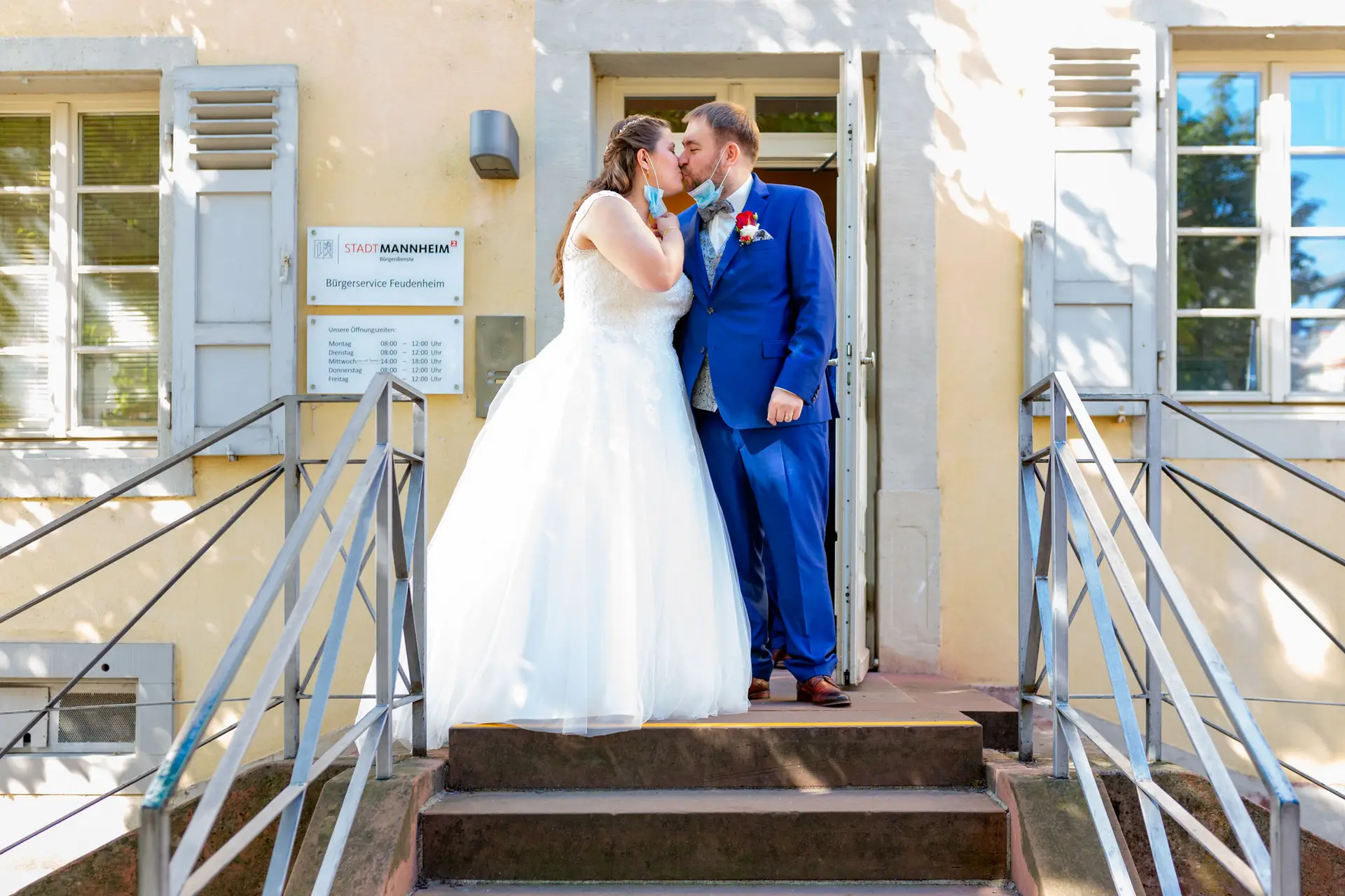 Brautpaar küsst sich auf den Stufen vor dem Standesamt Mannheim-Feudenheim