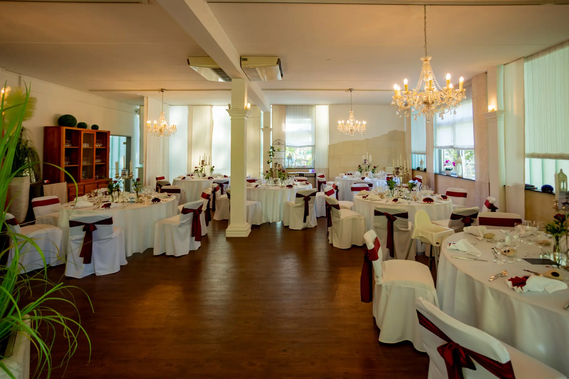 Festsaal im Luisenpark Mannheim mit gedeckten Tischen und großen Fenstern zum Park