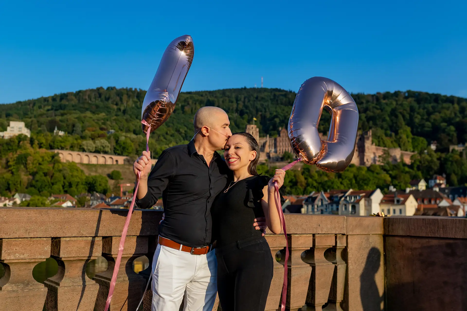 Paar mit Jahrestags-Ballons auf der Alten Brücke Heidelberg, Schloss im Hintergrund