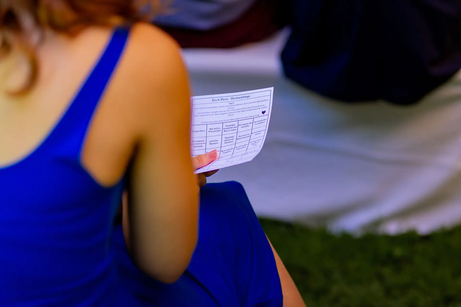 Traurednerin im blauen Kleid zeigt liebevolles Hochzeitsplakat mit den Namen Eva & Pierre