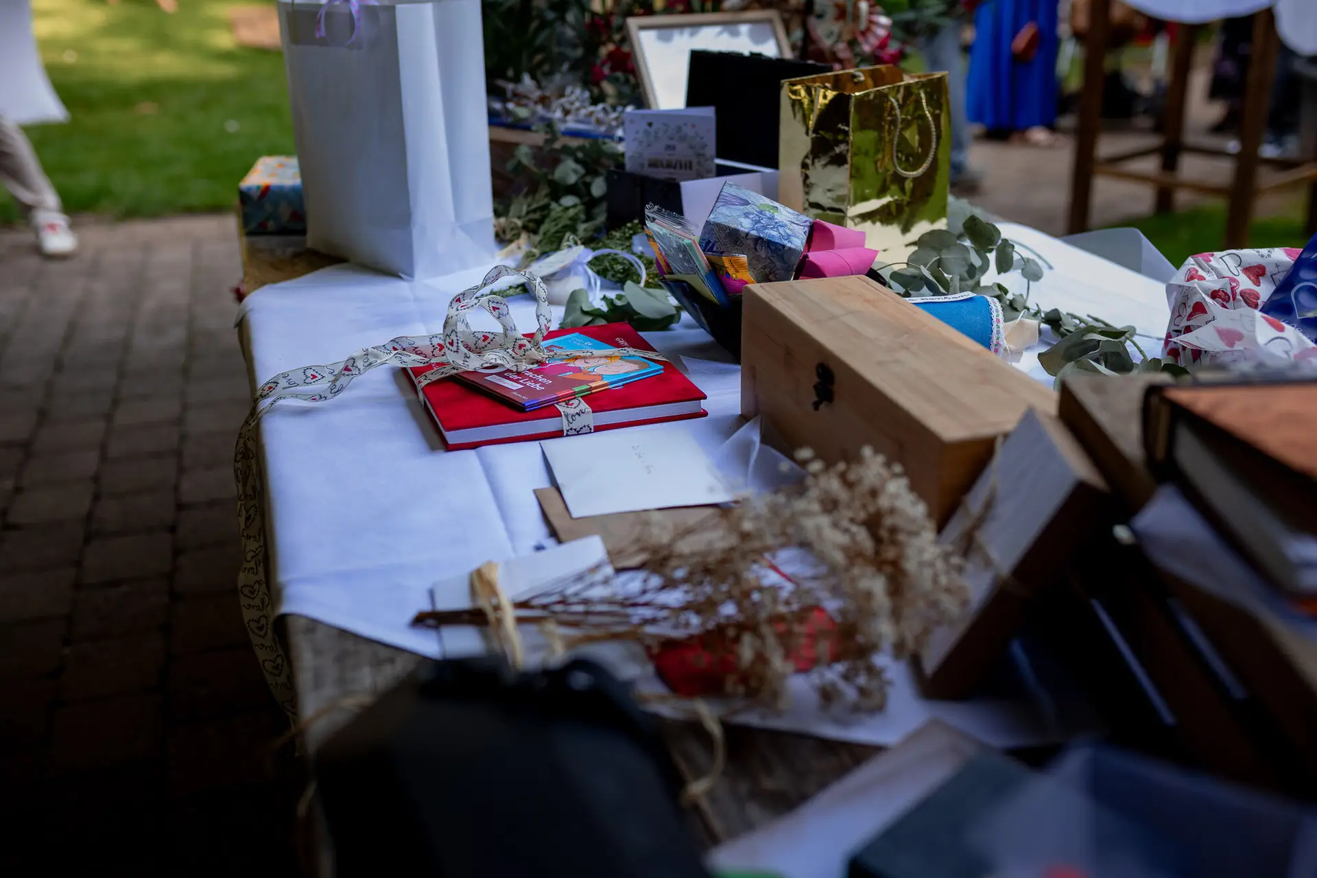 Geschenktisch im Freien mit bunt verpackten Hochzeitsgeschenken, Büchern und Schleifen