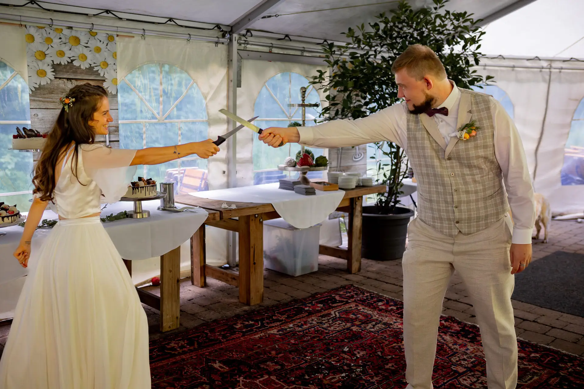 Braut schwingt spaßhaft das Tortenmesser beim Anschneiden, alle lachen