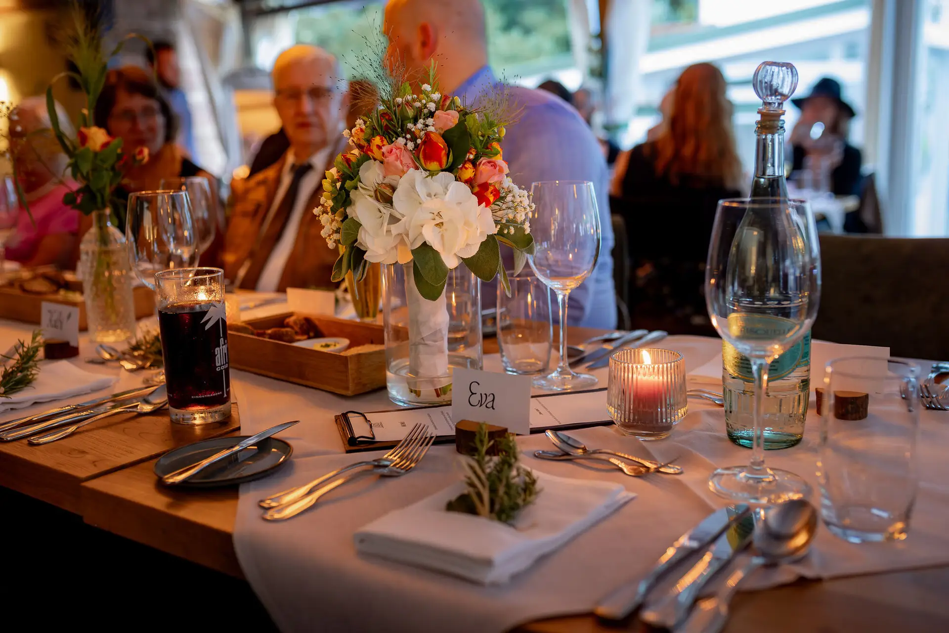 Rustikaler Esstisch mit Blumenarrangements, Champagner und Kerzenlicht zum Abendessen