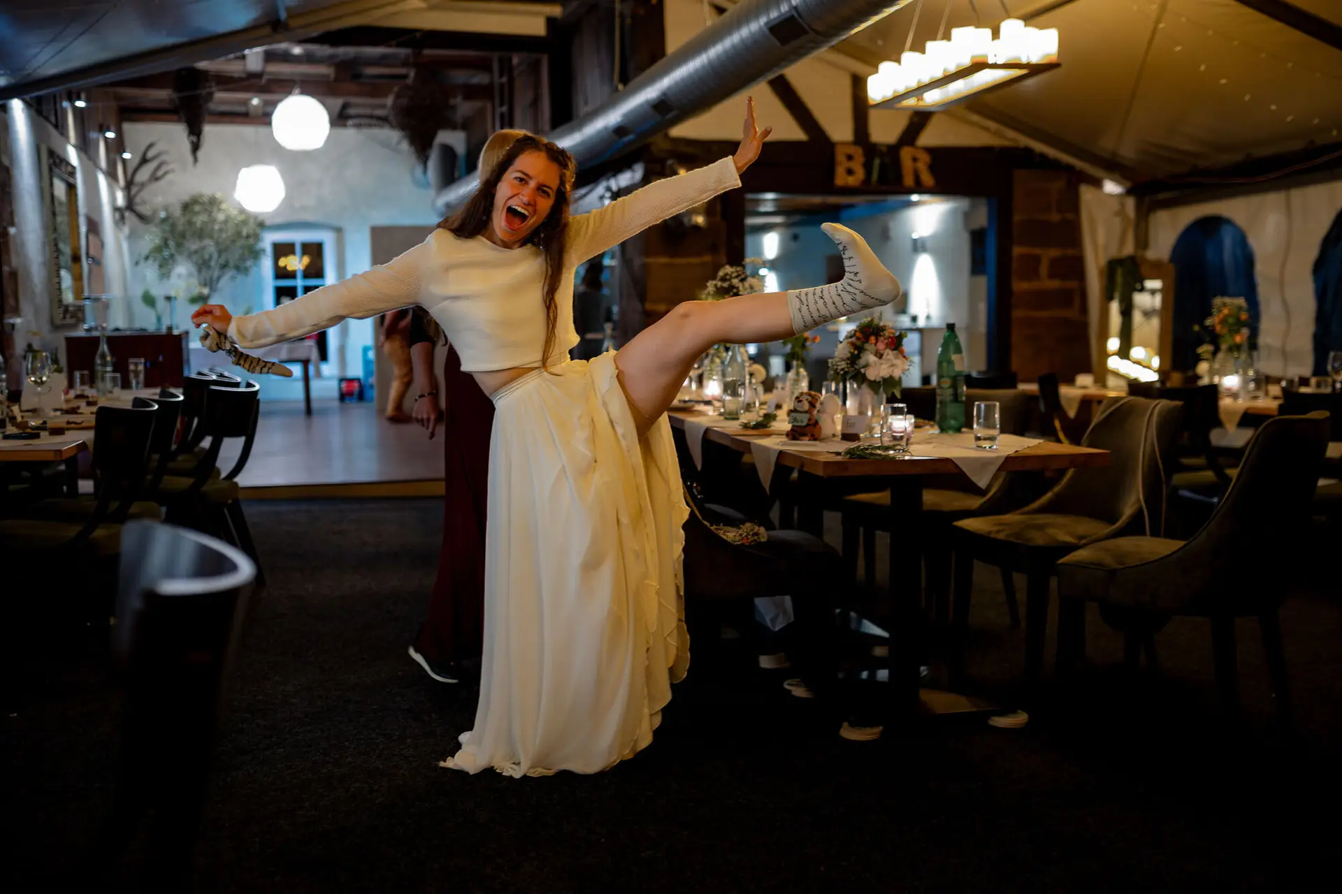 Braut tanzt ausgelassen und hält das Tortenmesser in die Luft – pure Freude bei der Late-Night-Party