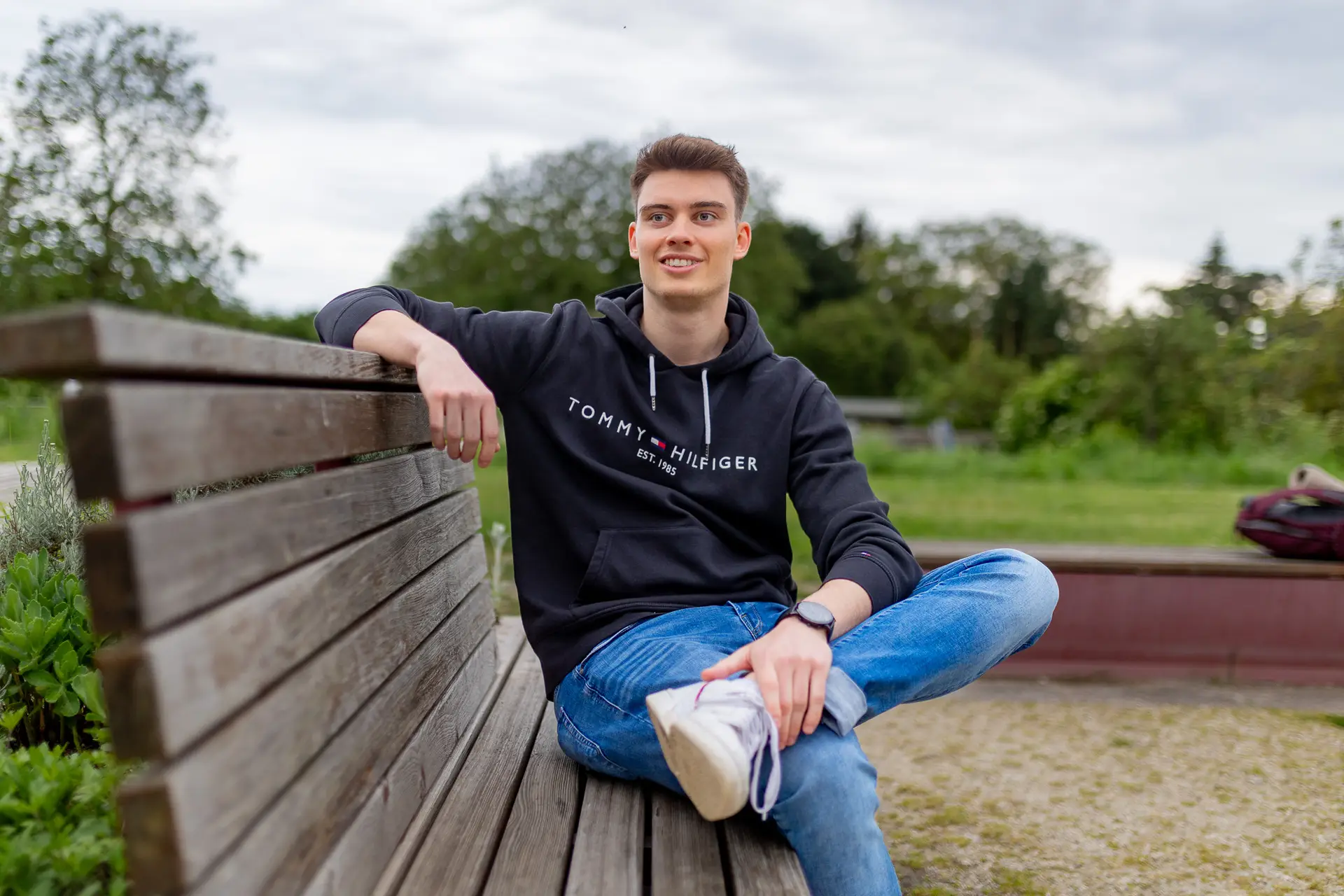 Sebastian sitzt entspannt auf einer Parkbank in der Bahnstadt