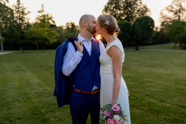 Hochzeitsfotograf in Worms: Brautpaar küsst sich im Sonnenuntergang auf einer Wiese im Schlossgarten beim Paarshooting.