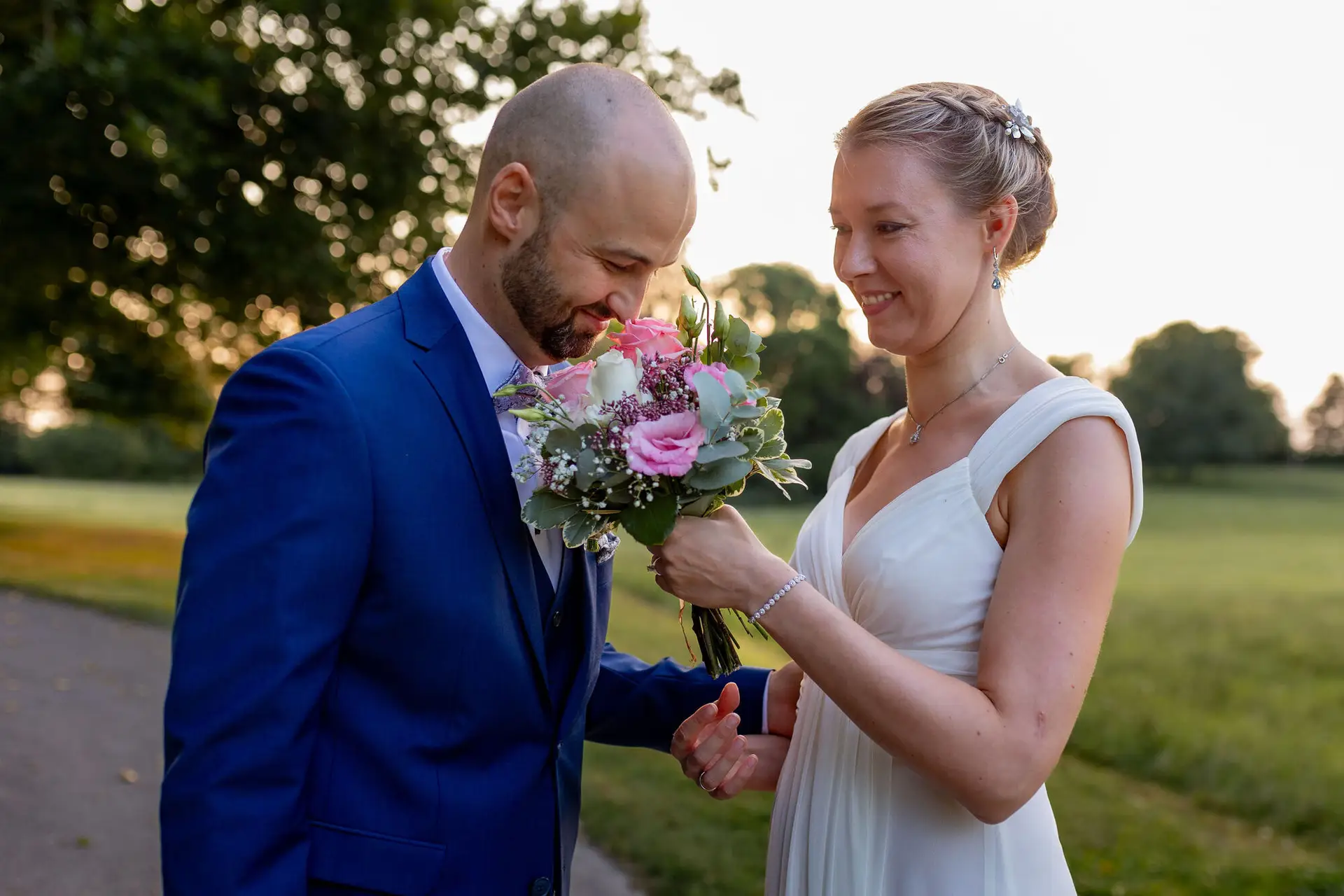 Braut zeigt dem Bräutigam den Ehering an ihrer Hand auf grüner Wiese
