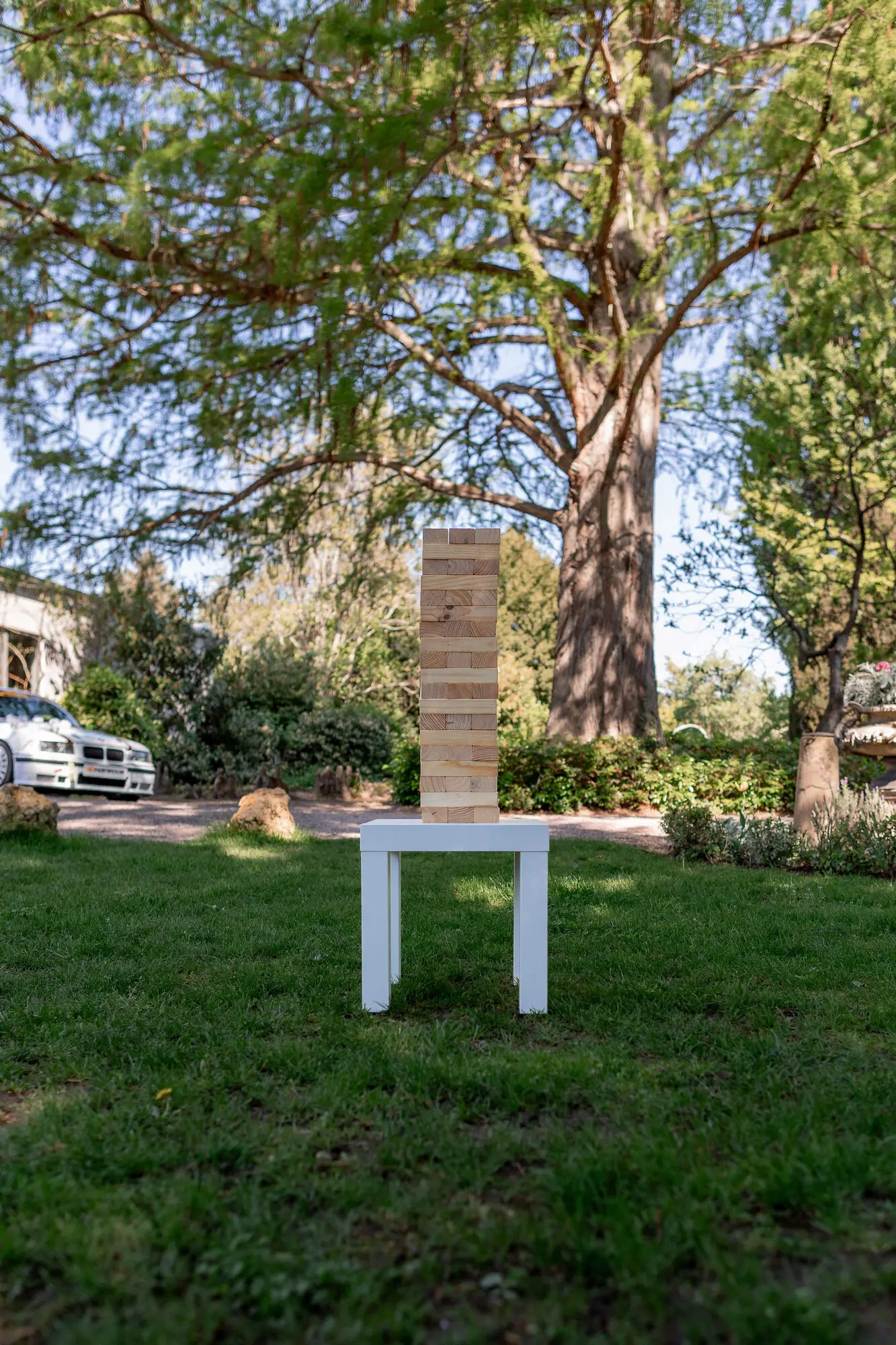 Jenga-Turm als Hochzeitsspiel auf weißem Beistelltisch im Gutsgarten