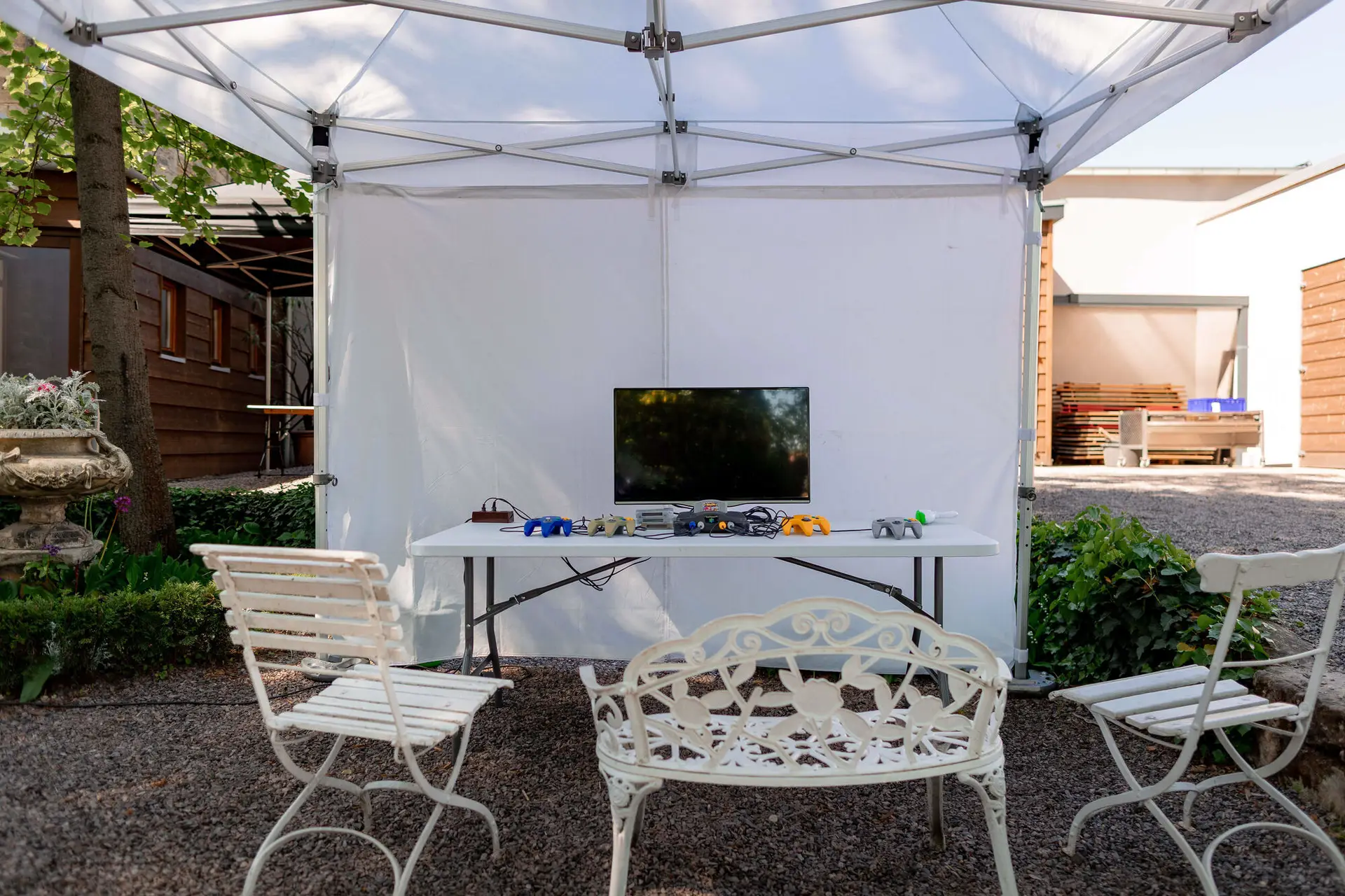 Gaming-Station mit Konsolen unter weißem Pavillon-Zelt im Garten