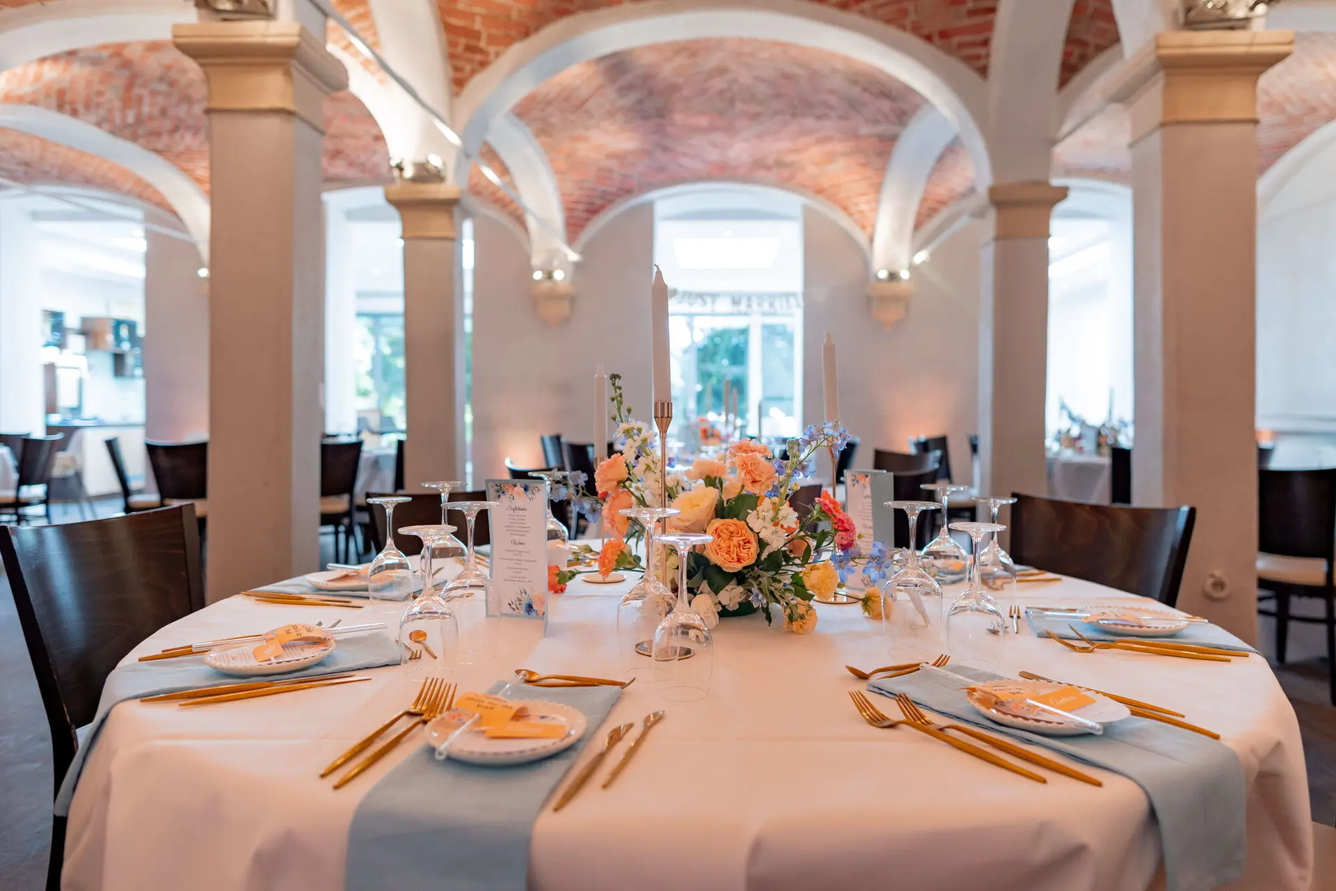 Festlich gedeckte Hochzeitstafel mit goldenen Details im Gewölbesaal