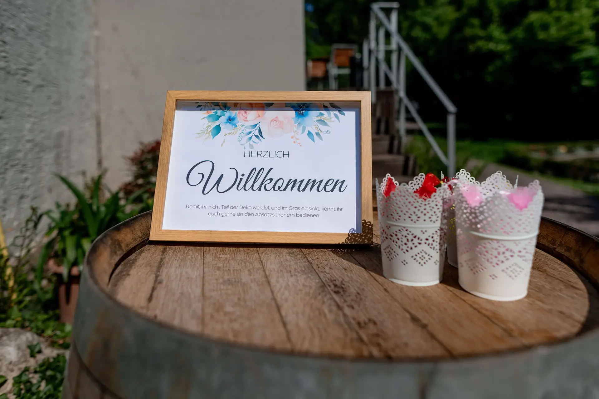 Herzlich Willkommen Schild mit Blumendeko auf rustikalem Weinfass