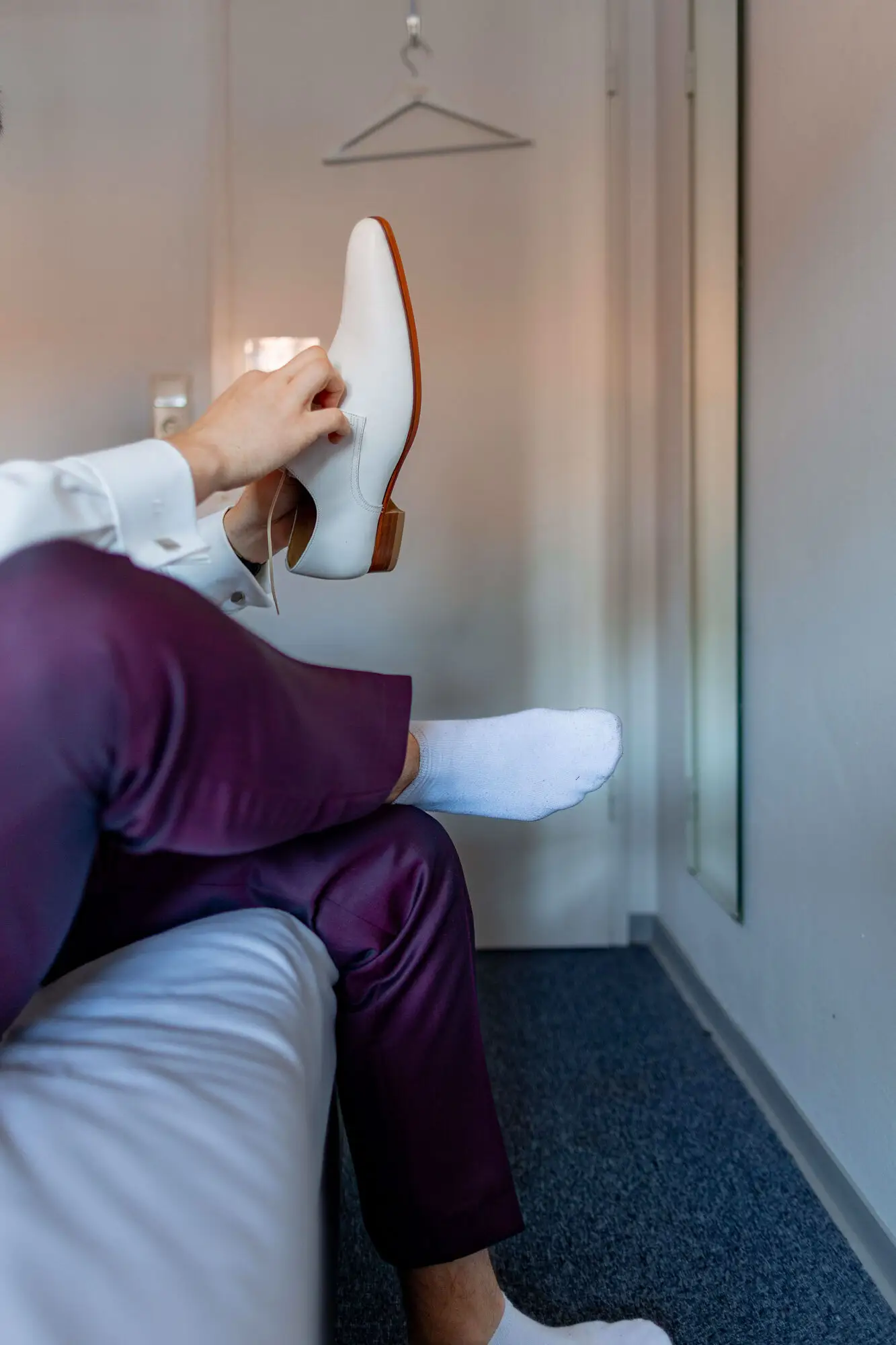 Bräutigam hält beigen Lederschuh in den Händen beim Getting Ready