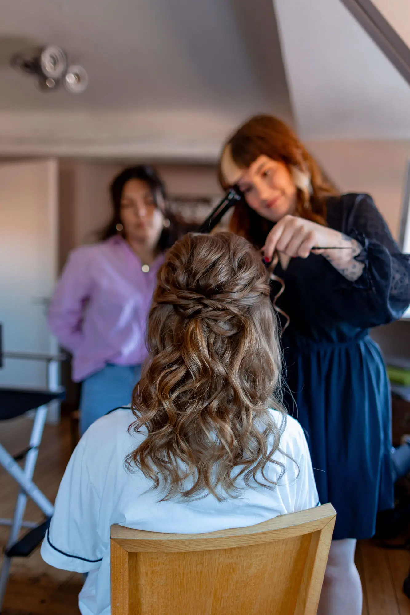 Friseurin stylt die Brautfrisur zu lockigen Hochsteckfrisur