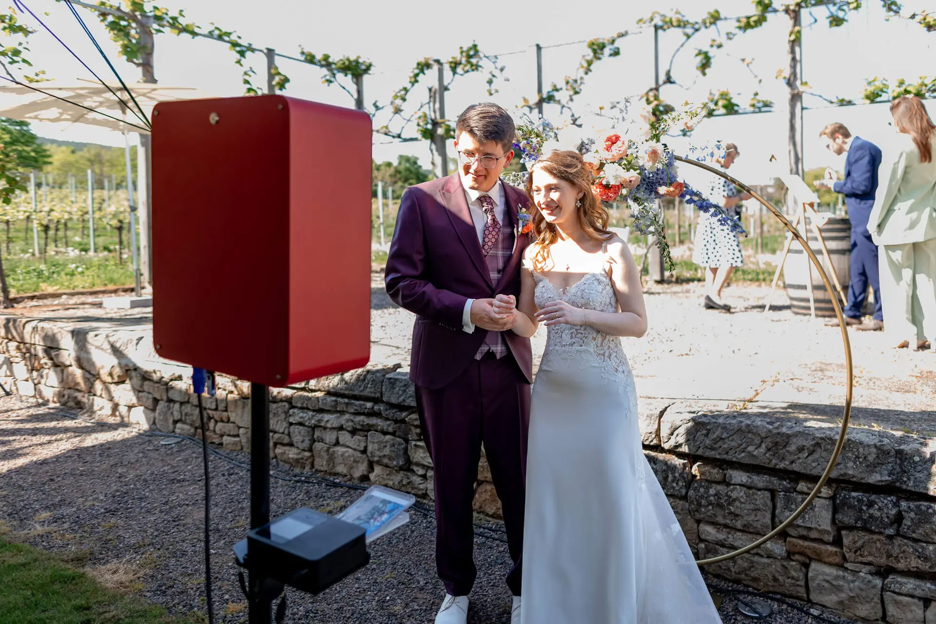 Brautpaar sitzt entspannt auf Holzbank im sonnigen Weinberg