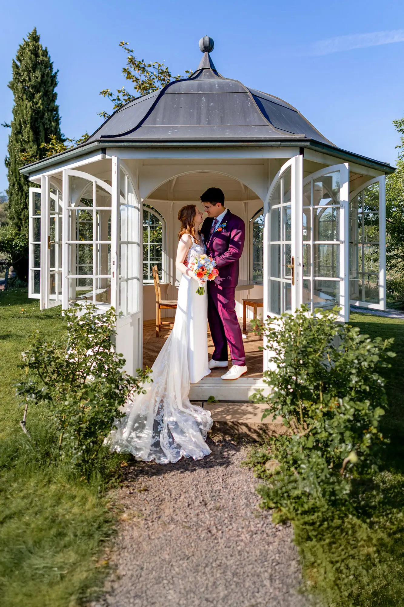 Brautpaar küsst sich im romantischen weißen Pavillon mit geöffneten Türen