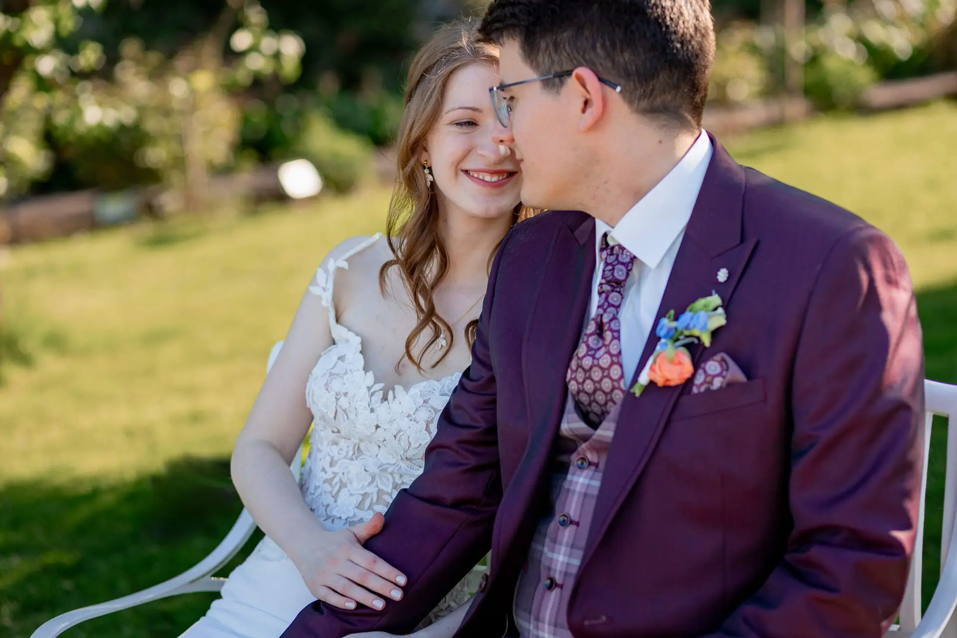 Brautpaar umarmt sich liebevoll im sonnendurchfluteten Gutsgarten