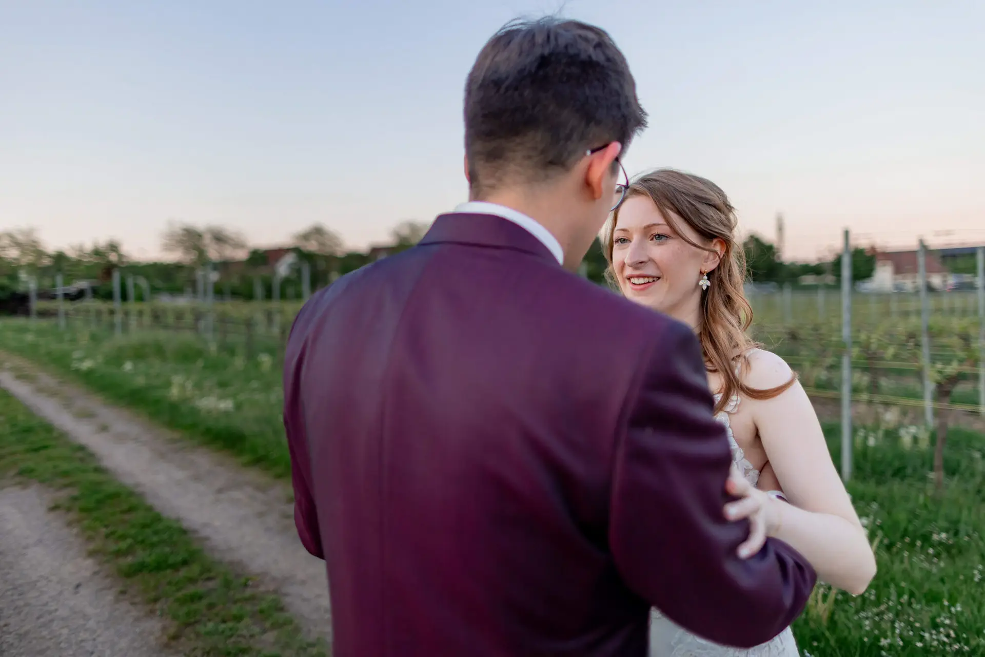 Strahlende Braut lacht glücklich beim Tanzen mit dem Bräutigam im Weinberg