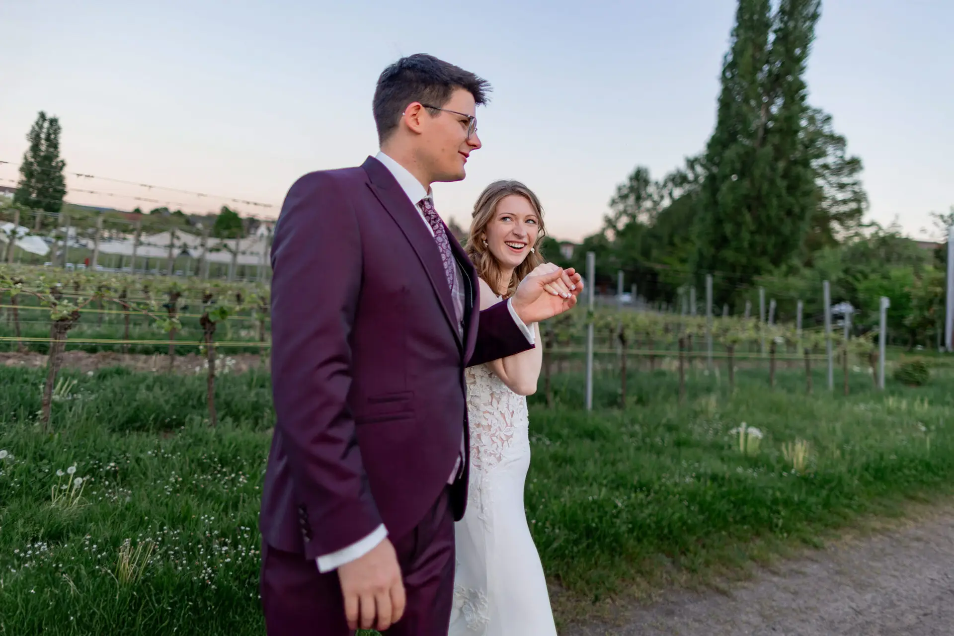 Brautpaar lacht gemeinsam beim Tanzen im warmen Abendlicht der Weinberge