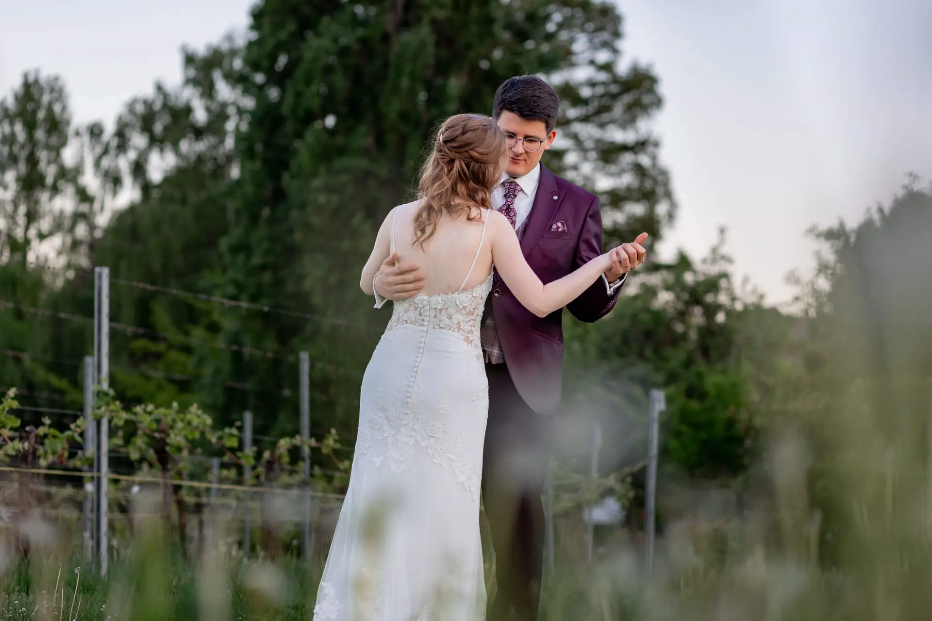 Verliebtes Brautpaar umarmt sich innig beim Tanzen im Weinberg bei Sonnenuntergang