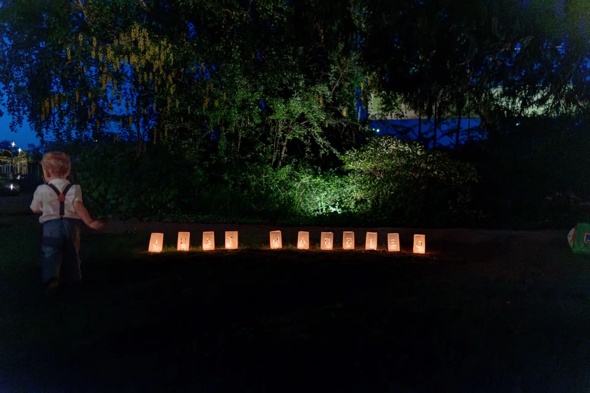 Leuchtende Lichtertüten mit JUST MARRIED Schriftzug säumen abends den Weg im Gutspark