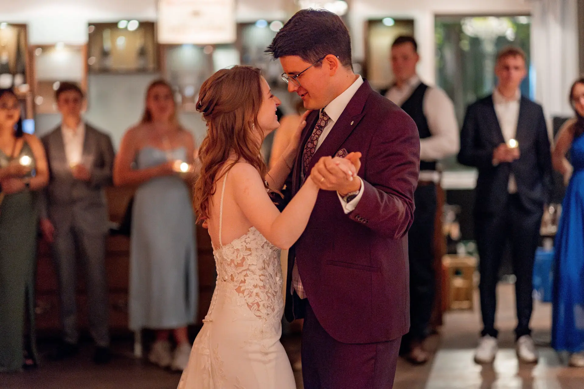 Brautpaar tanzt ersten Tanz umgeben von Gästen im Festsaal