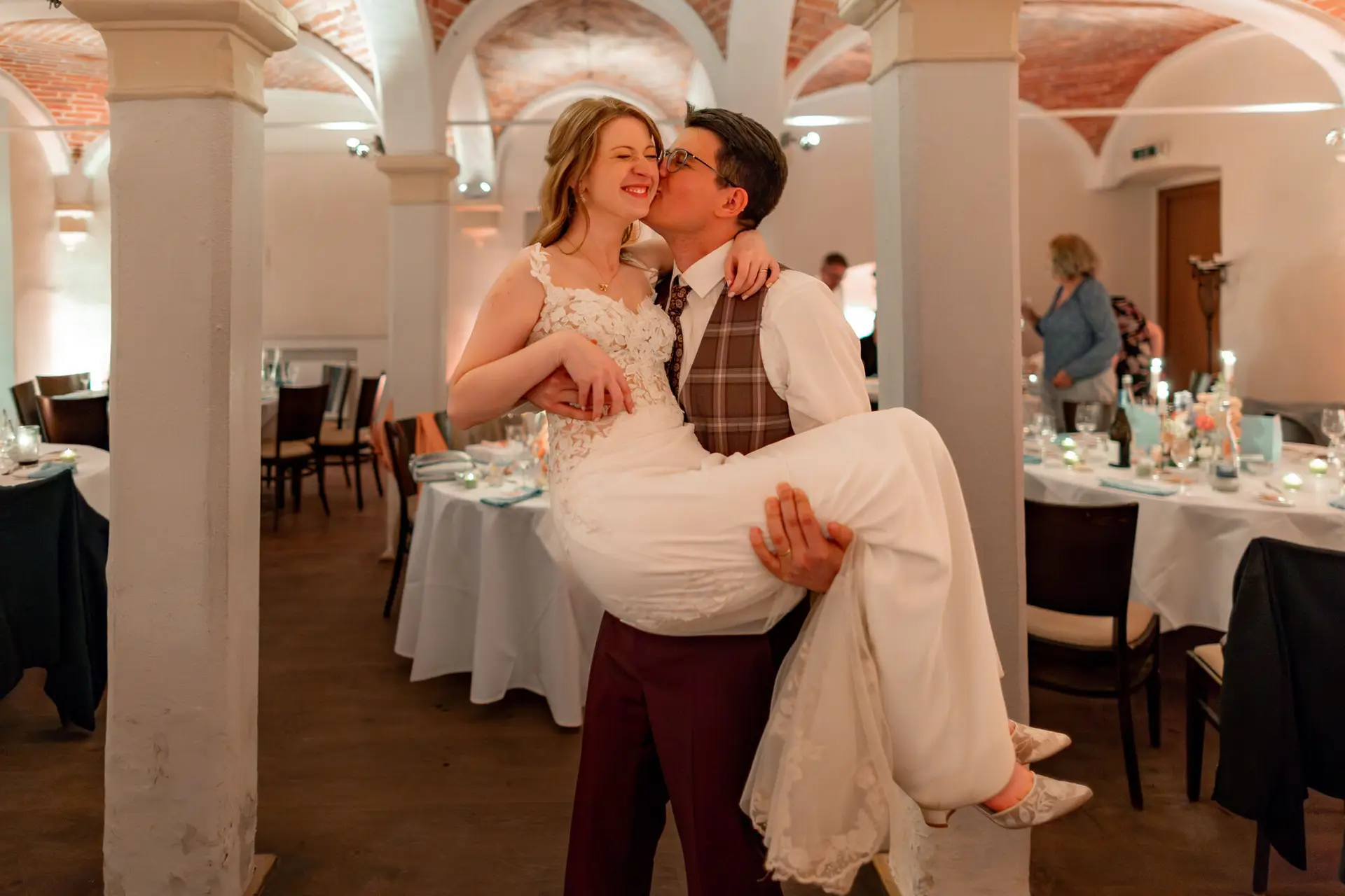 Bräutigam trägt seine Braut auf den Armen im Kreuzgewölbesaal