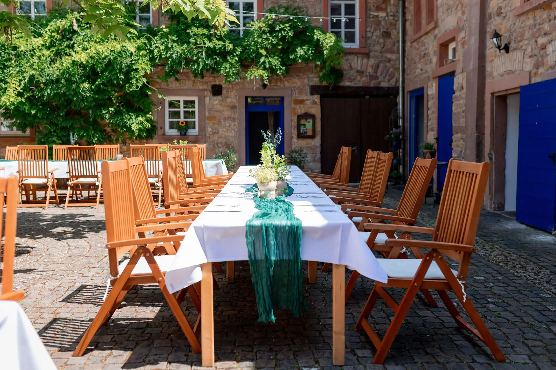 Innenhof mit langen Hochzeitstafeln und grünem Läufer