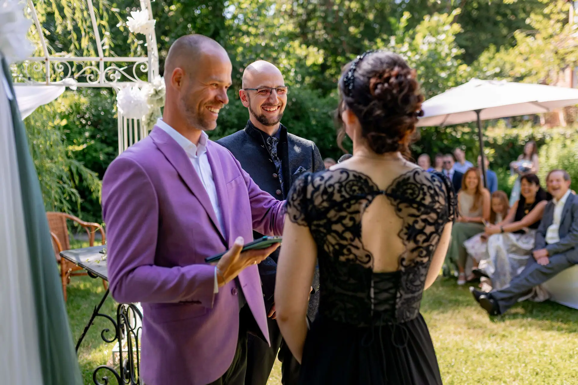 Brautpaar mit Officiant im Garten