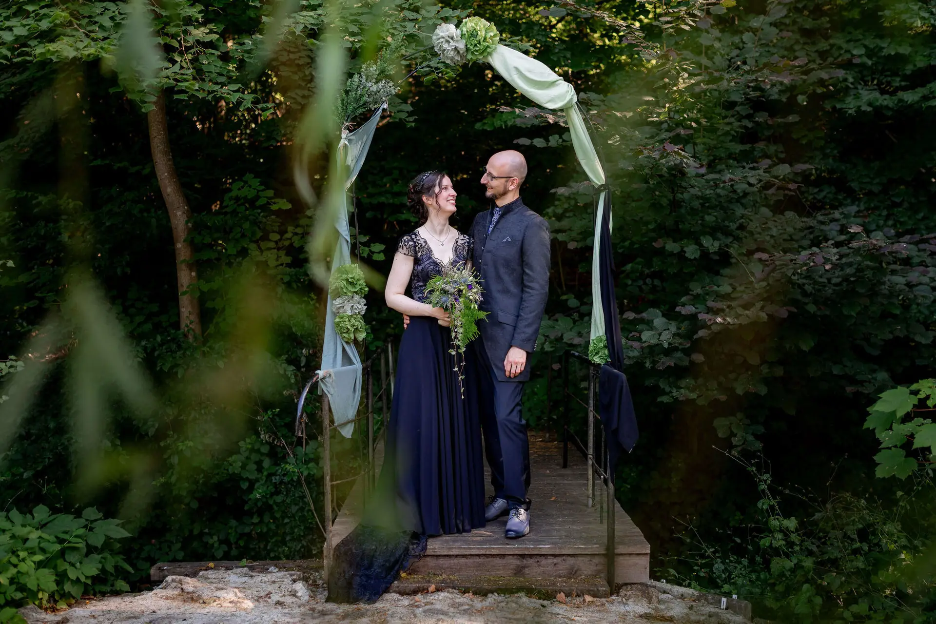 Braut und Bräutigam umarmen sich vor Steinmauer