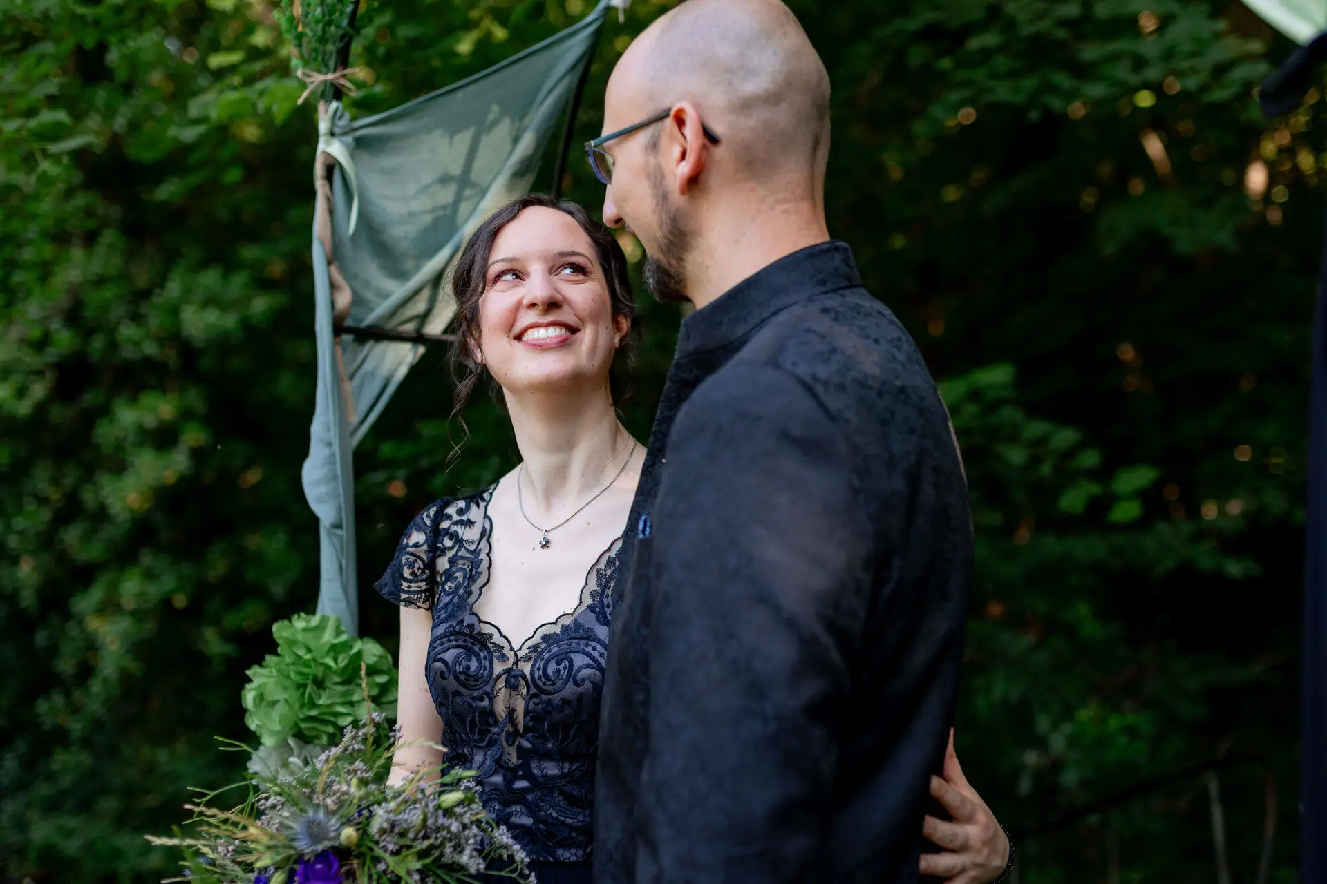 Liebevolles Brautpaar unter der grünen Laube