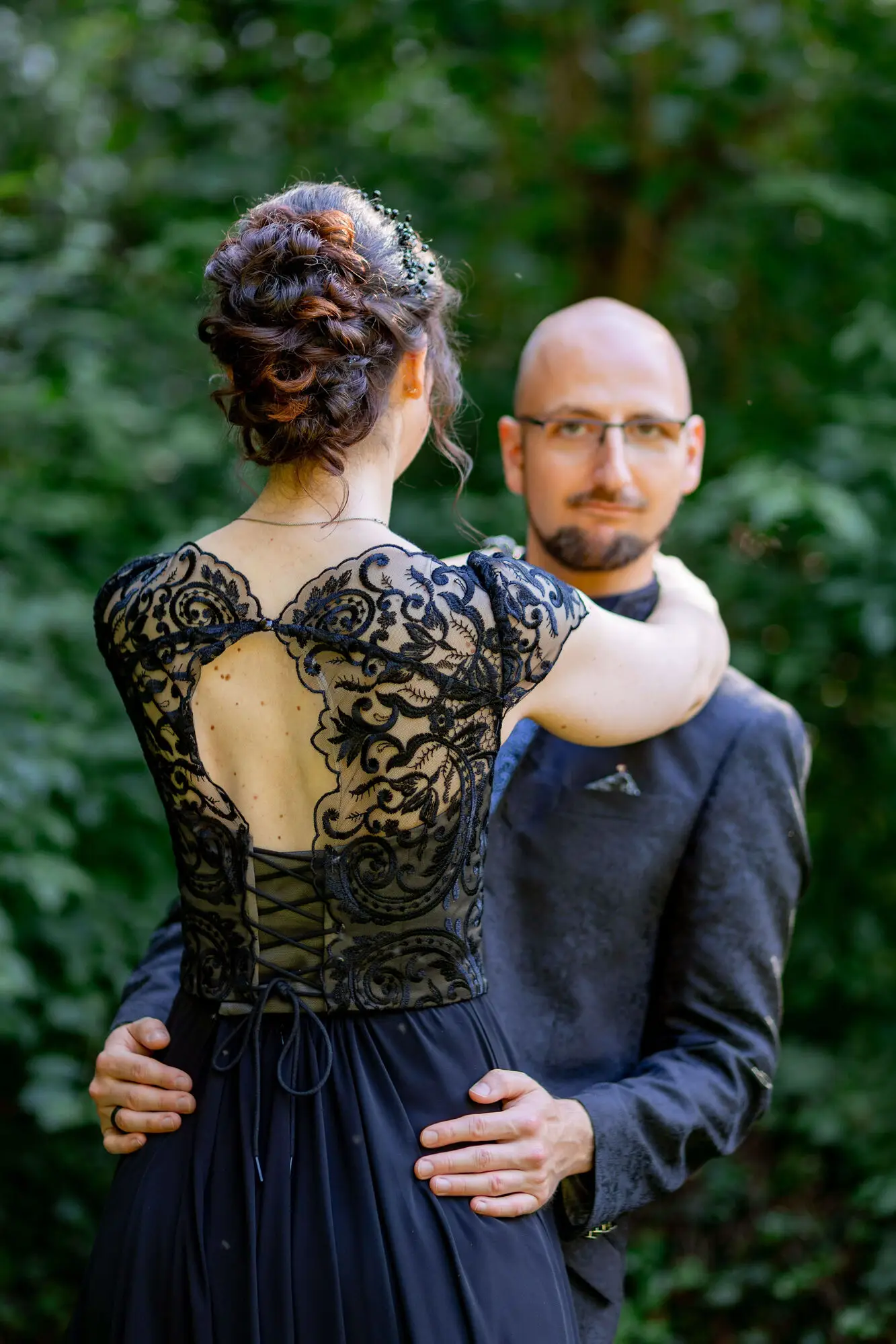 Brautpaar lächelt durch Blattwerk im Garten