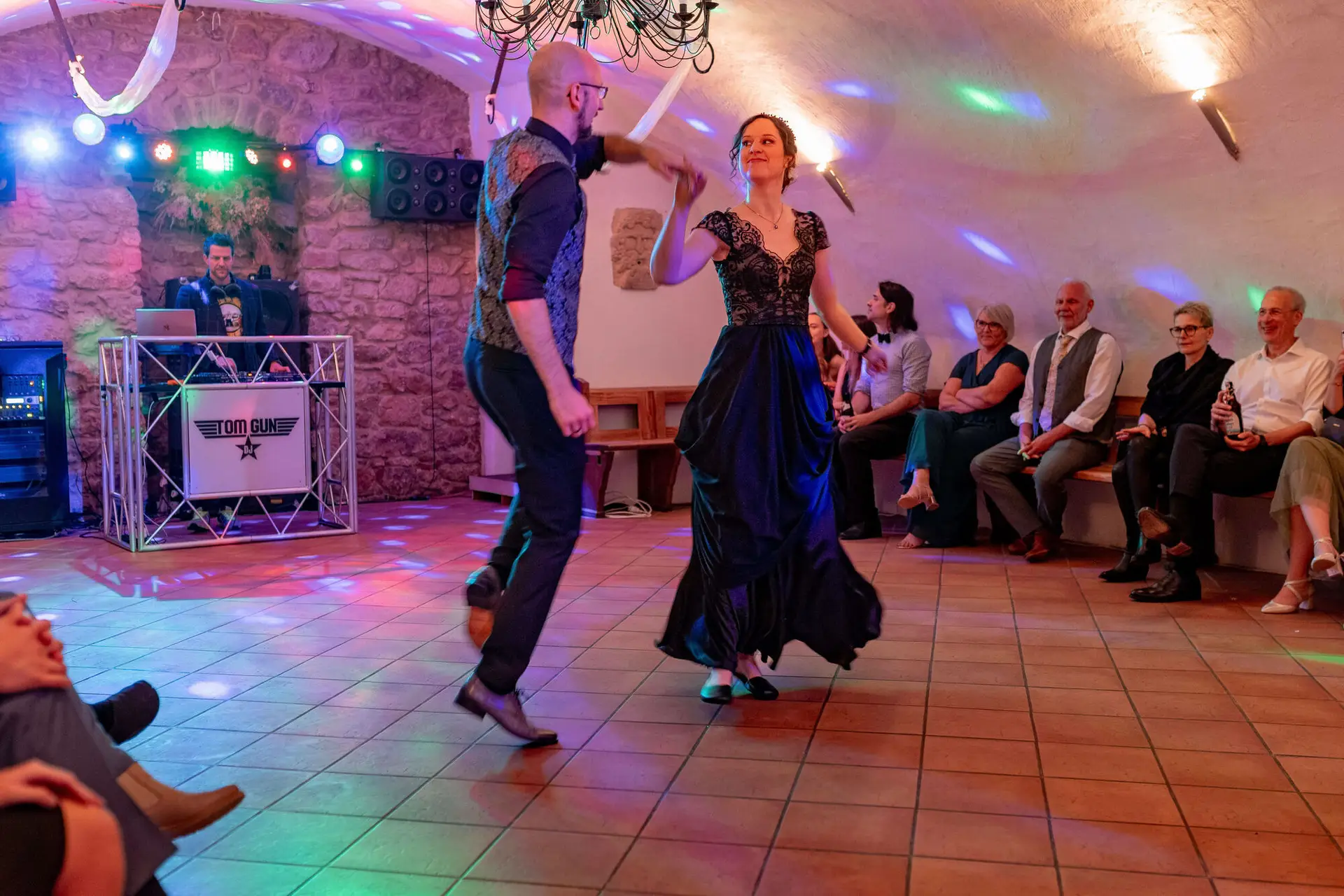 Brautpaar tanzt vor Gästen mit Partykeller-Beleuchtung