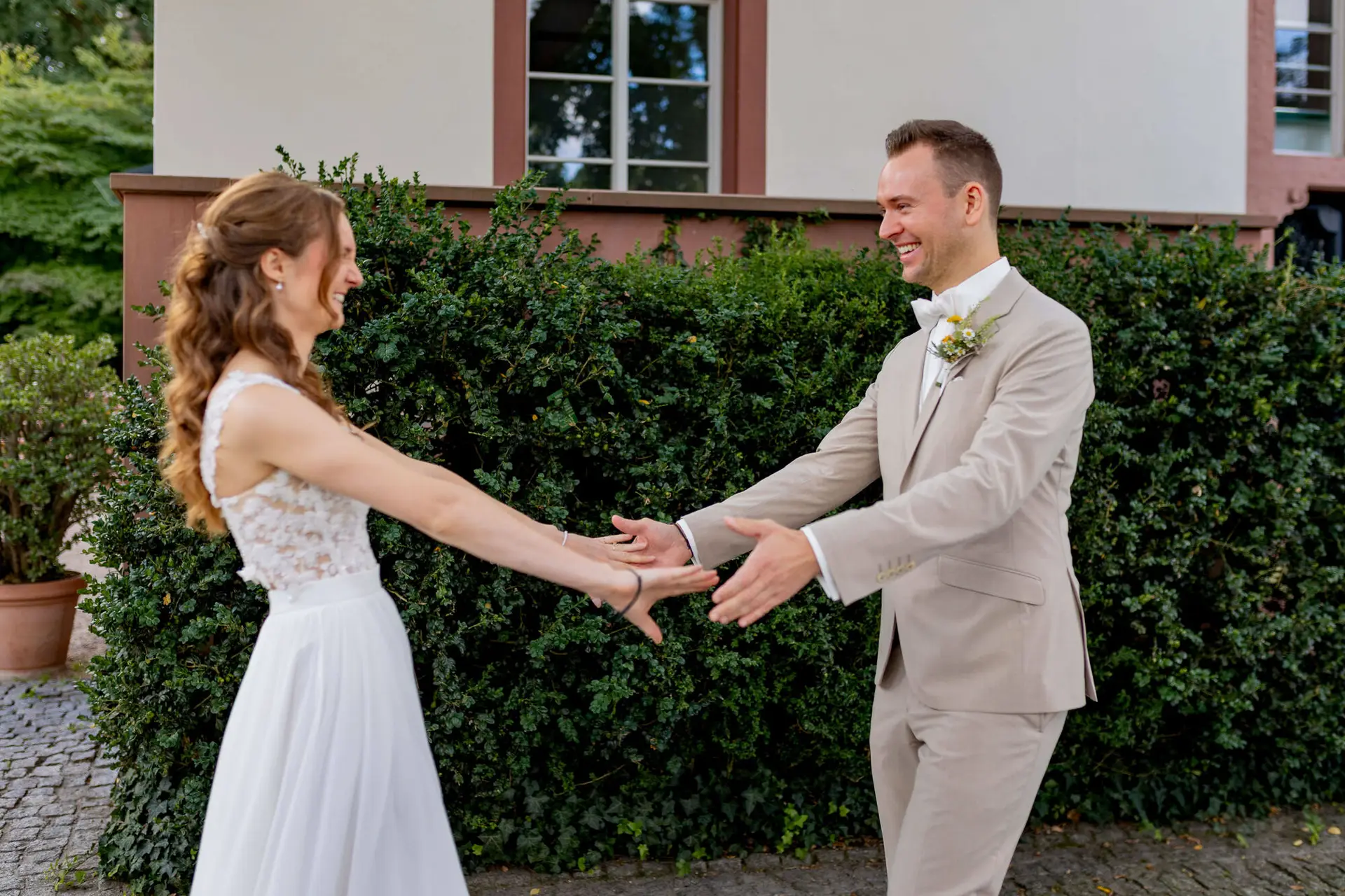 Brautpaar hält sich an den Händen und lächelt sich beim First Look an