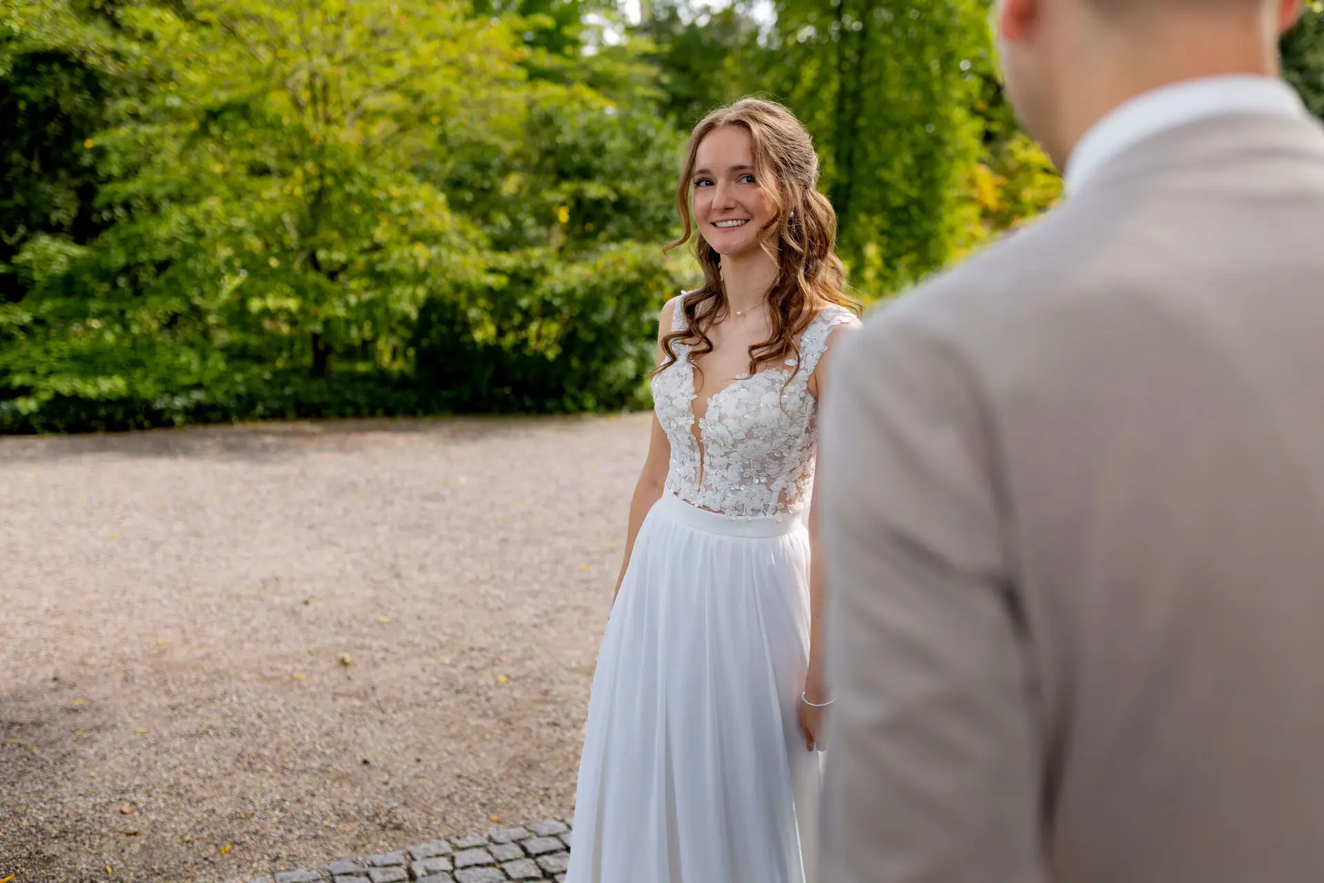 Braut lächelt den Bräutigam strahlend an im grünen Garten