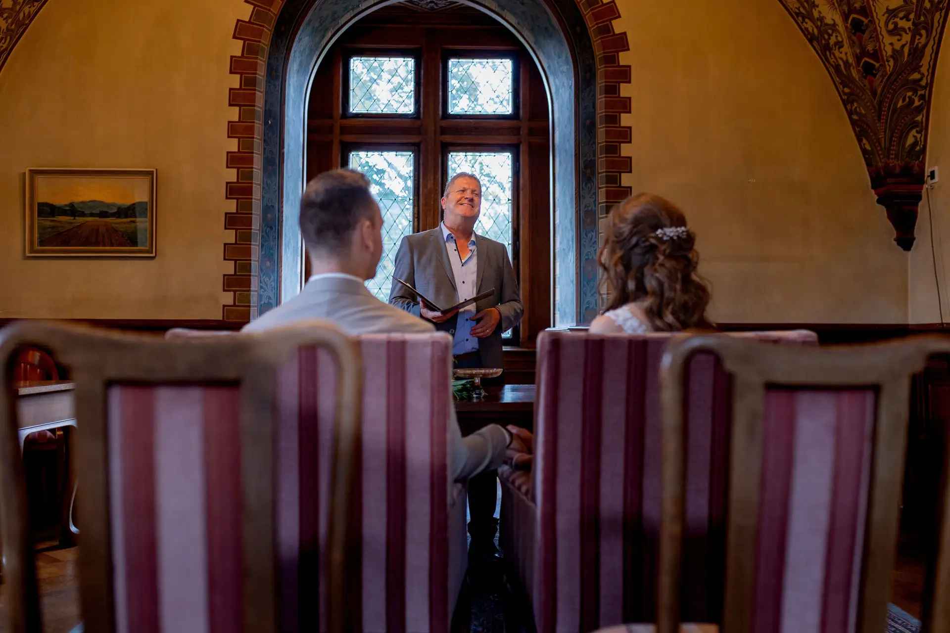 Standesbeamter spricht zum Brautpaar im historischen Trausaal