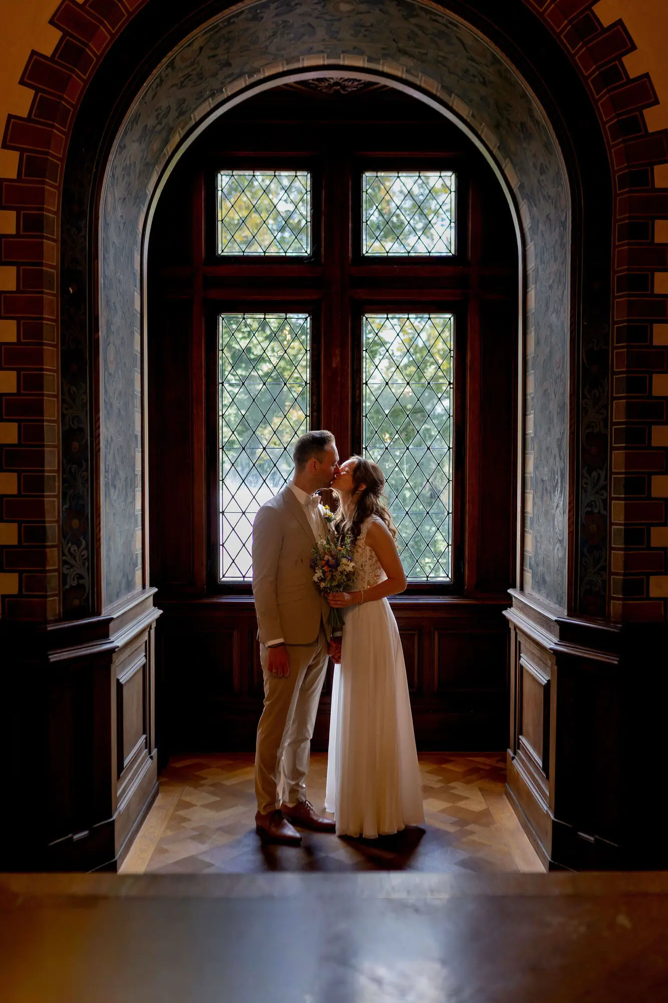 Brautpaar küsst sich vor dem Bogenfenster im Standesamt Weinheim