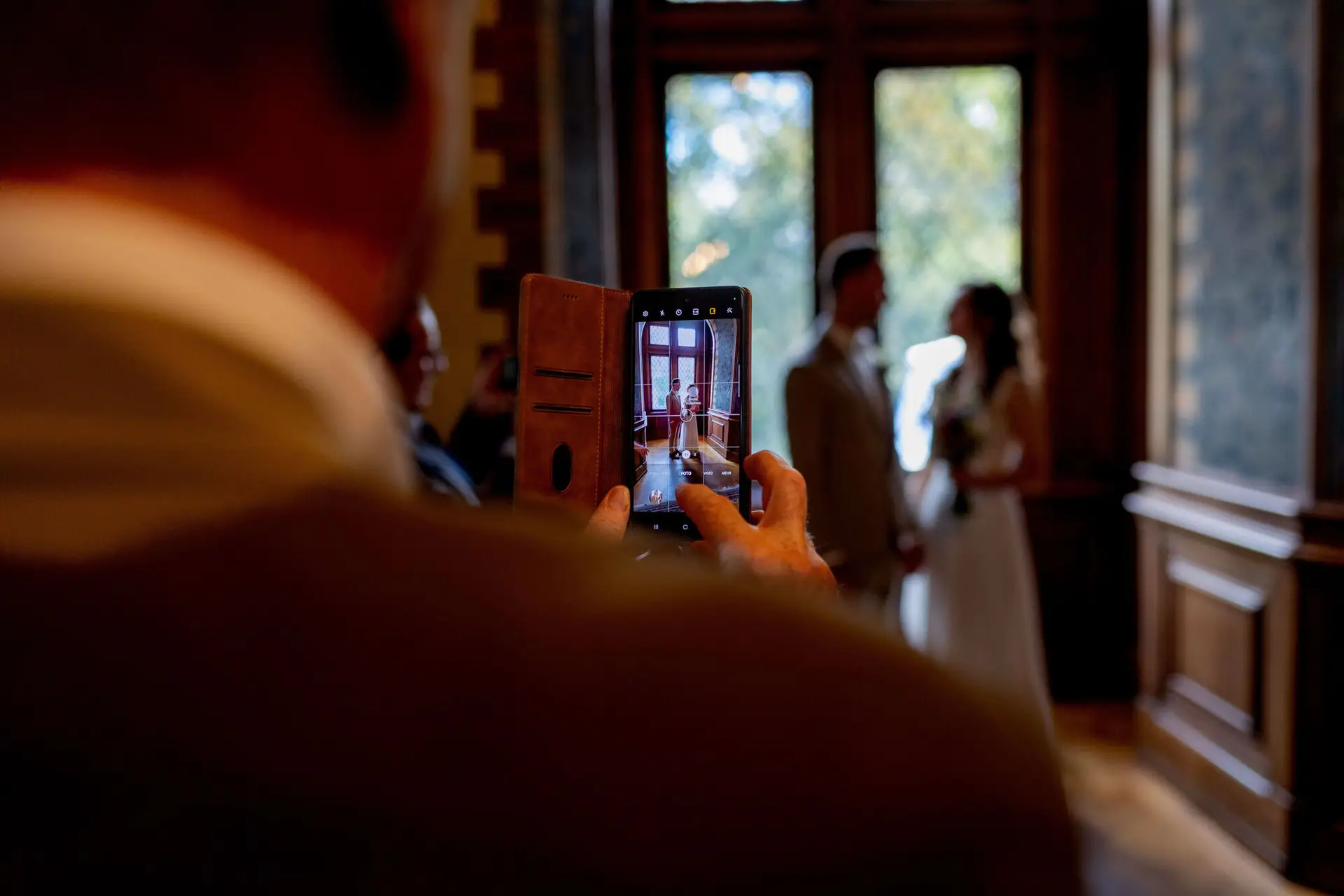 Hochzeitsgast filmt das Brautpaar mit dem Smartphone im Standesamt