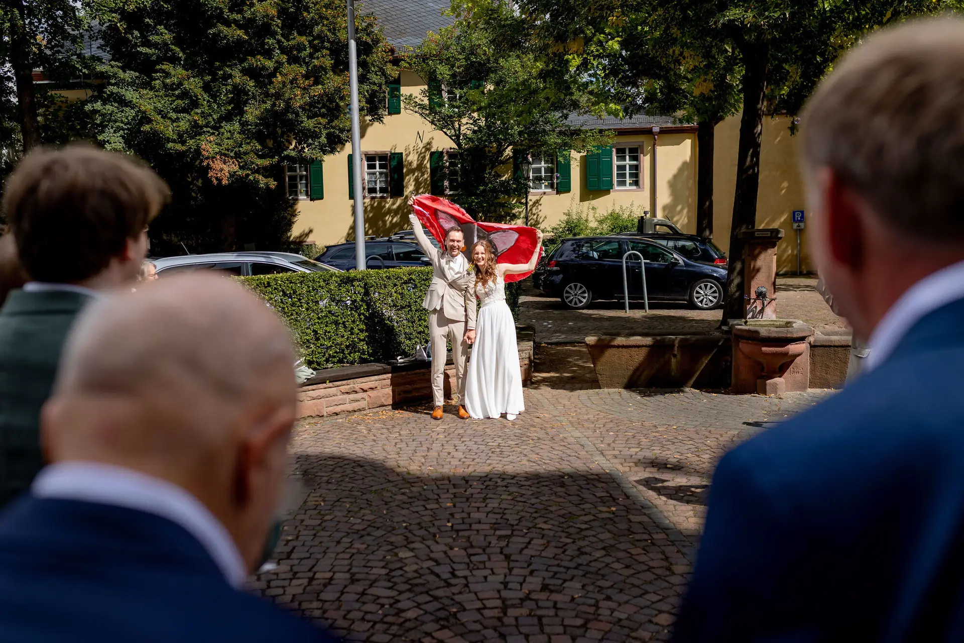 Brautpaar präsentiert stolz das ausgeschnittene Herz vor den applaudierenden Gästen