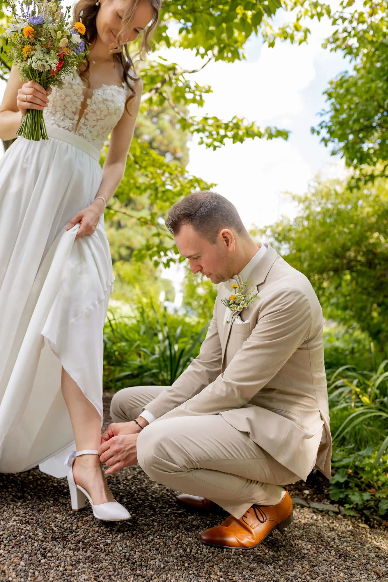Bräutigam richtet der Braut den Schuh im Garten des Hermannshofs