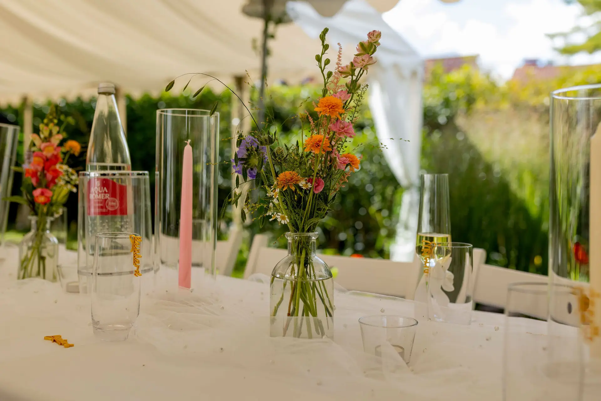 Tischdekoration mit bunten Wildblumen und rosa Kerzen im Gartenzelt