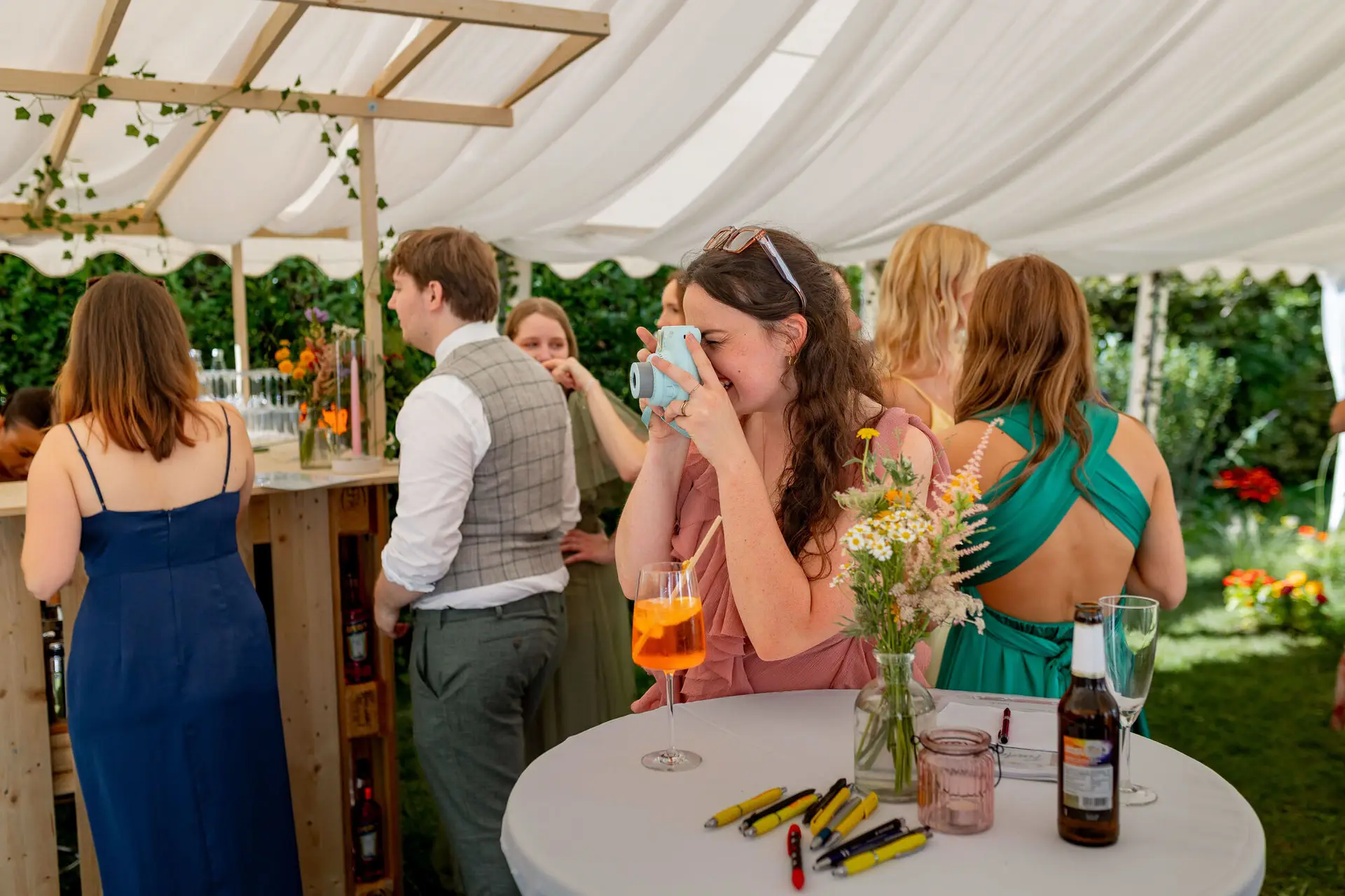 Gästin fotografiert lachend mit Instax-Kamera unter dem Zelt
