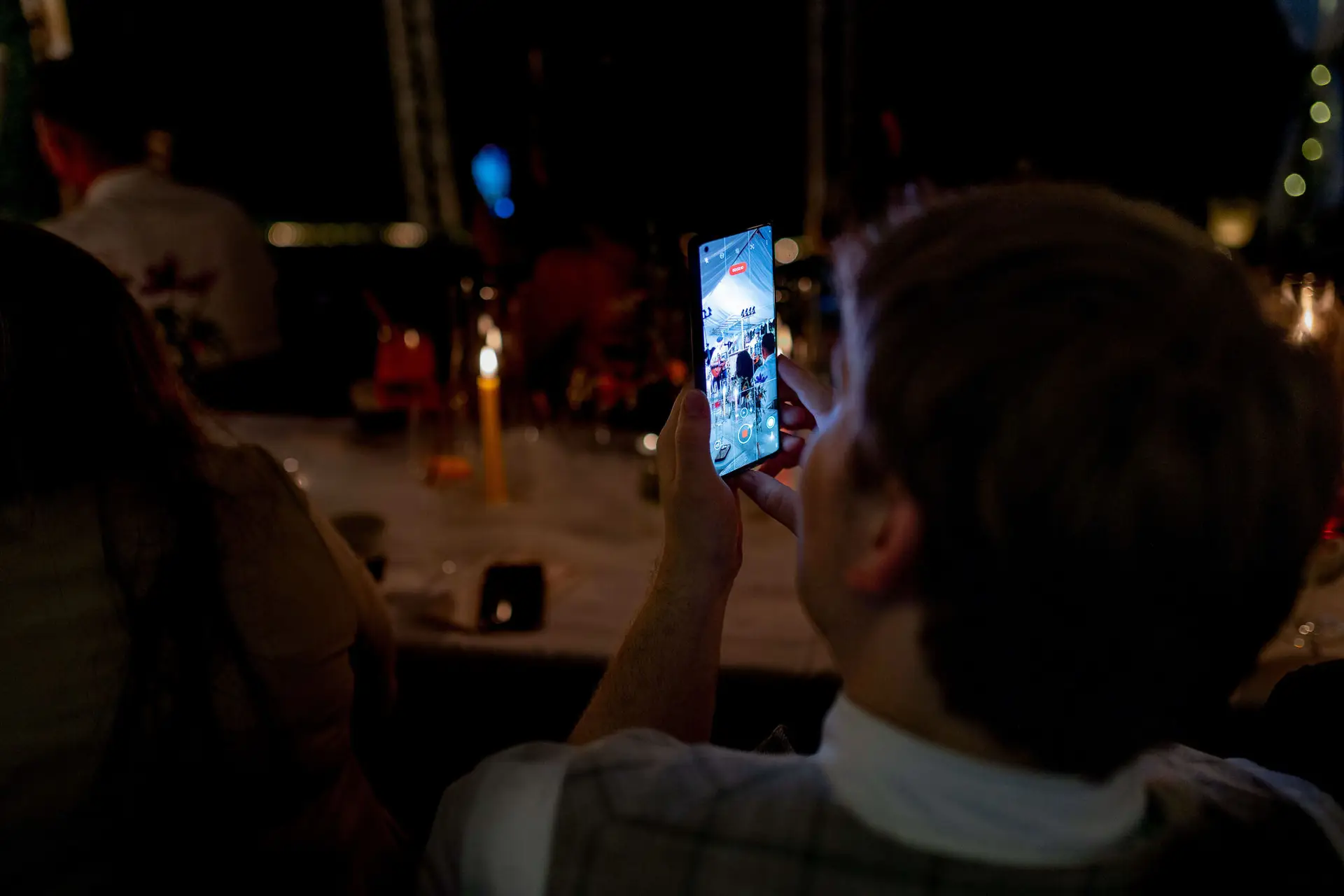 Bräutigam filmt mit dem Smartphone die Abendunterhaltung im Garten